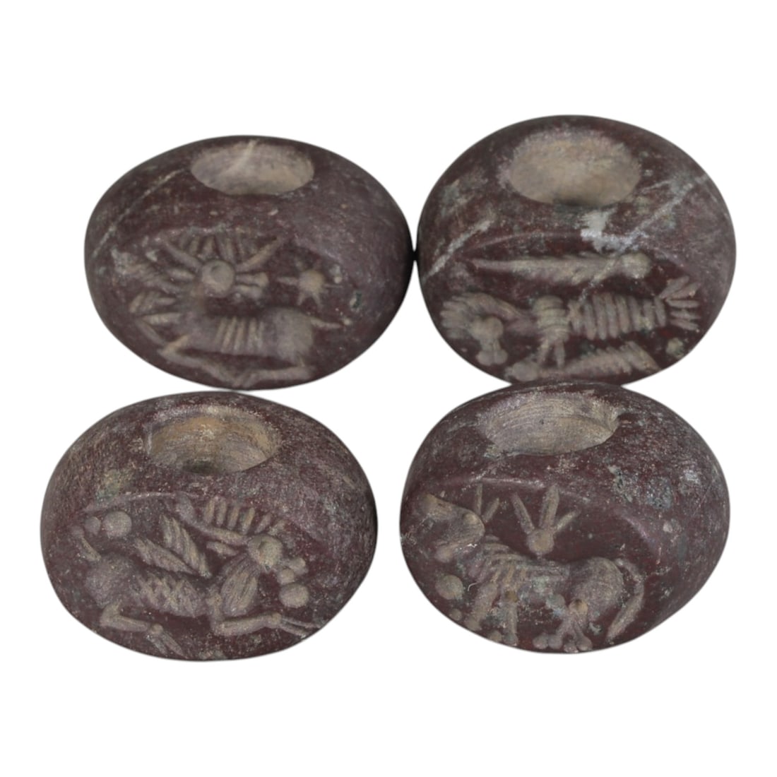 Lot of 4 Ancient Sasanian Stone Stamp Seals, Circa 3rd-7th Century CE, 67WP: A collection of four Sasanian period stamp seals, carved from reddish stone, each with a central drilled hole for suspension. The seals are decorated with characteristic Sasanian zoomorphic motifs, in