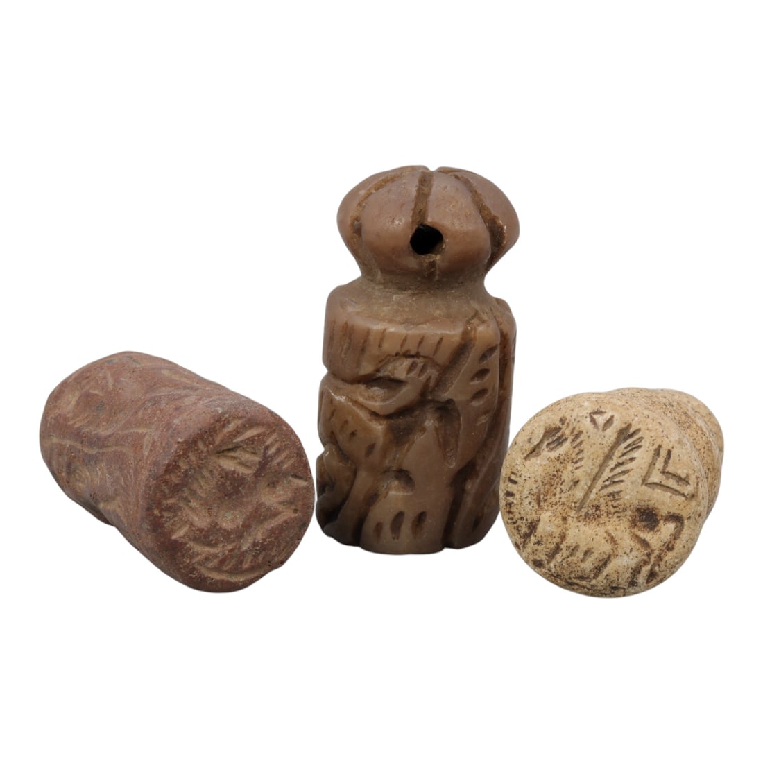 Lot of 3 Ancient Mesopotamian Cylinder Seal and Stamps, 79WM: A collection of three ancient Mesopotamian stone seals and stamps, carved from brown and light-toned stone. The set includes: a reddish-brown cylinder seal engraved with zoomorphic motifs, a carved br