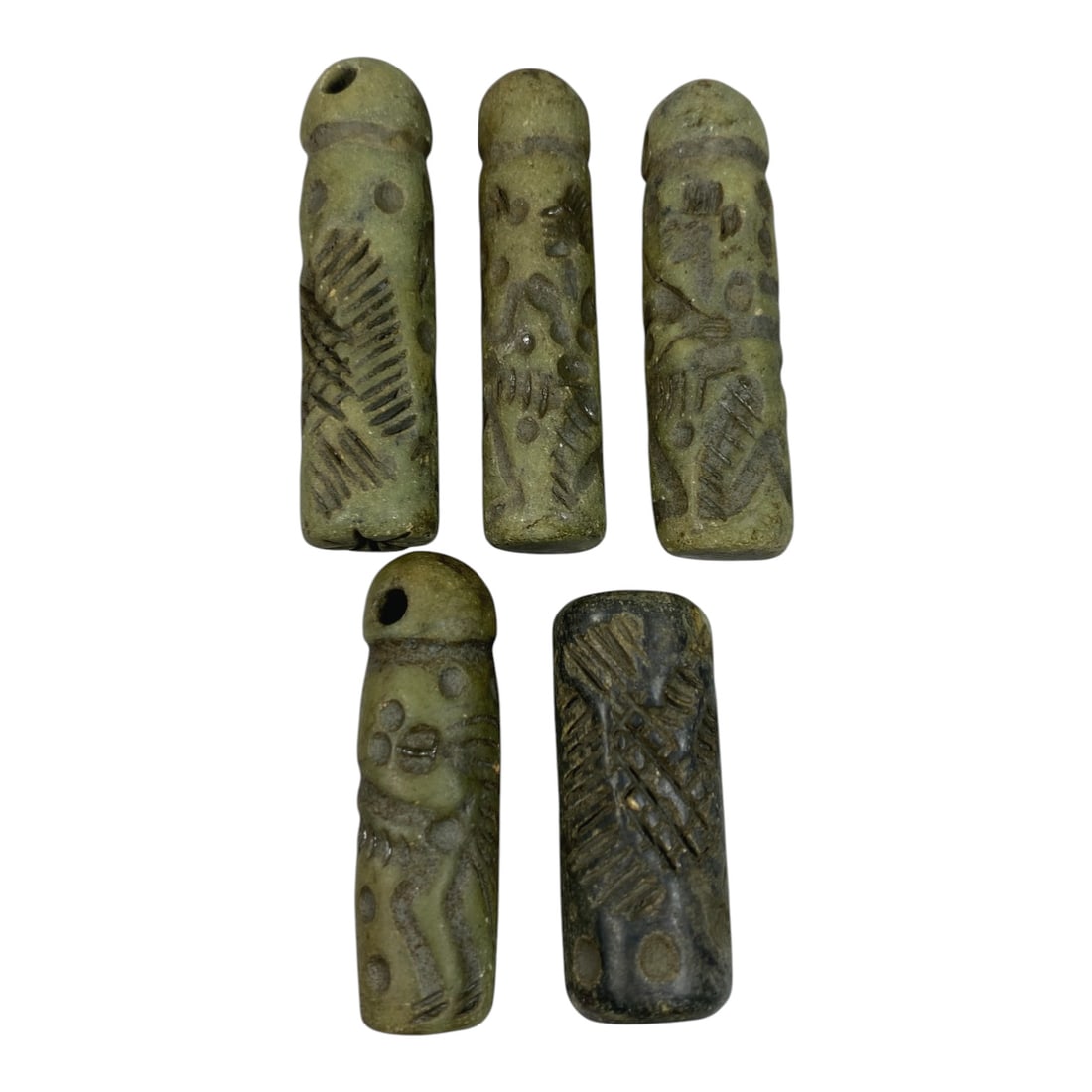 A Lot of 5 Ancient Mesopotamian Serpentine Cylinder Seals, 43WP: A curated lot of five ancient Mesopotamian-style cylinder seals, carved from serpentine stone with natural patination and wear consistent with age. The collection features four seals with domed tops a
