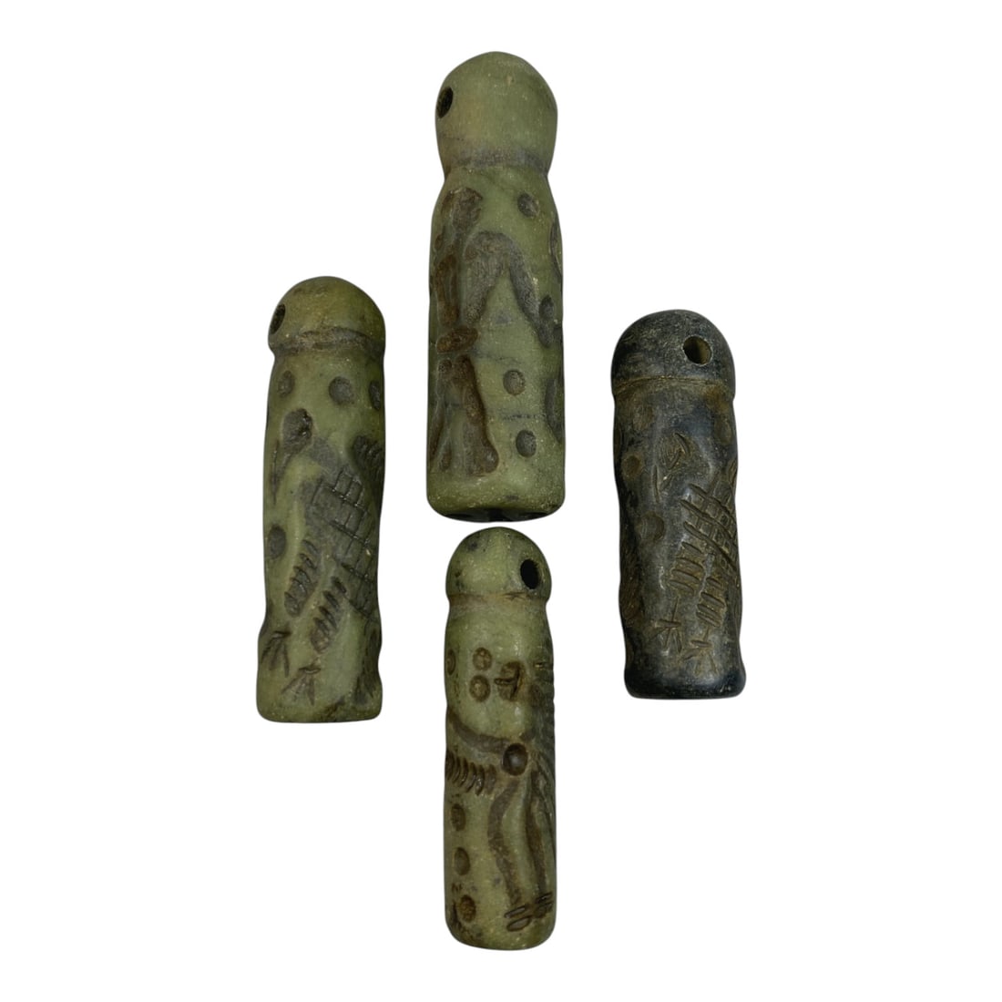 A Lot of 4 Ancient Mesopotamian Serpentine Cylinder Seals, 46WP: A curated lot of four ancient Mesopotamian-style cylinder seals, carved from serpentine stone with natural patination and wear consistent with age. Each seal features a domed top with a suspension hol
