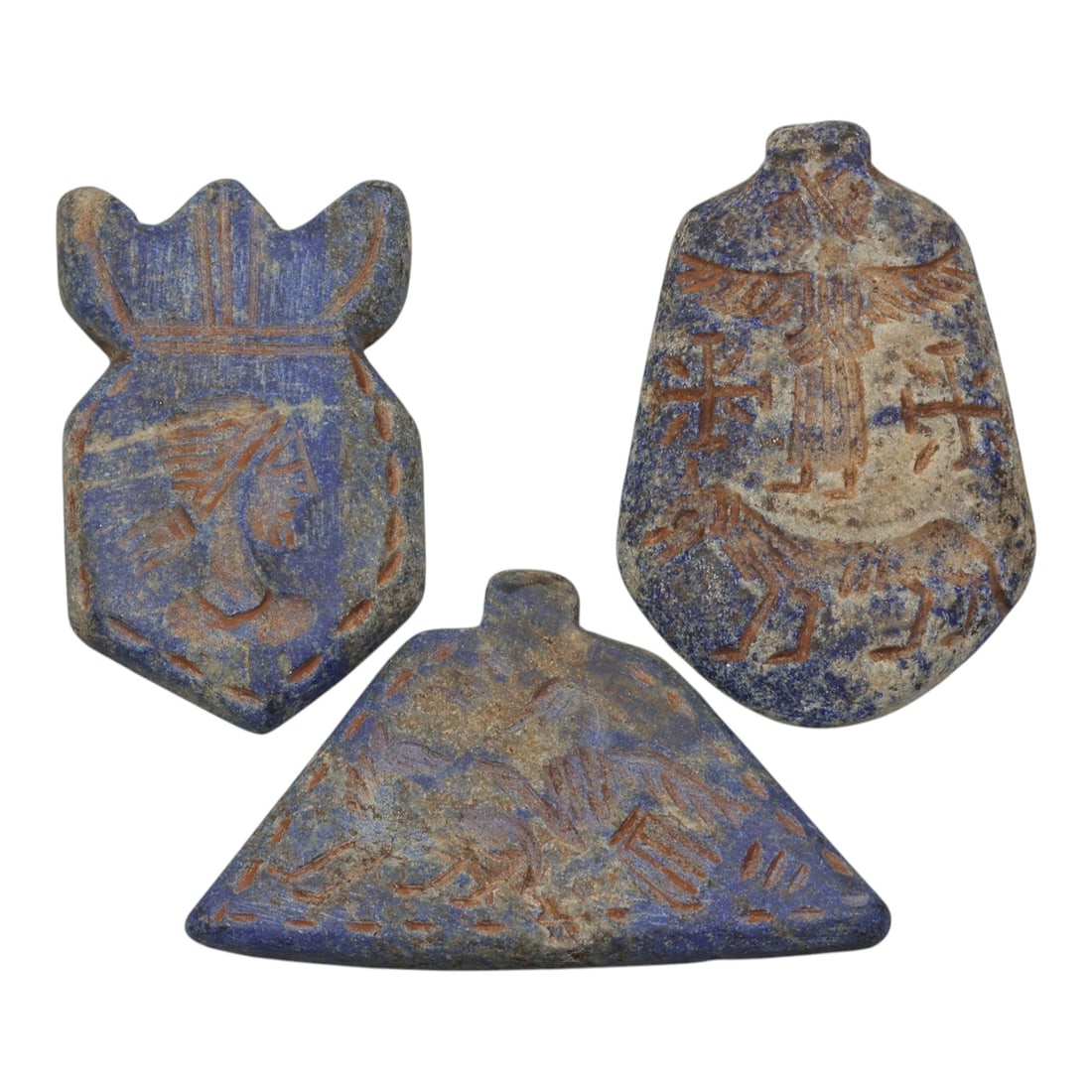 A Lot of 3 Ancient Near Eastern Lapis Lazuli Amulets, 38WP: A curated lot of three ancient Near Eastern-style amulets, carved from lapis lazuli stone. Each piece features incised decoration in reddish pigment, depicting varied iconography including a crowned p