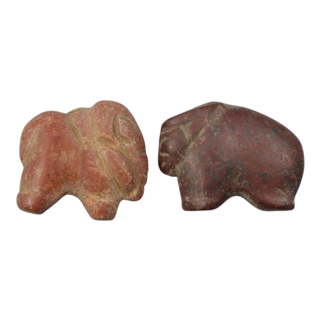 Lot of 2 Ancient Near Eastern Red Stone Zoomorphic Amulets, c. Iron Age to Sasanian Period, 49WL: Carved from weathered red stone, this pair of stylized zoomorphic amulets depicts quadruped forms, likely elephants or similar creatures, with simplified anatomical detailing and suspension grooves fo