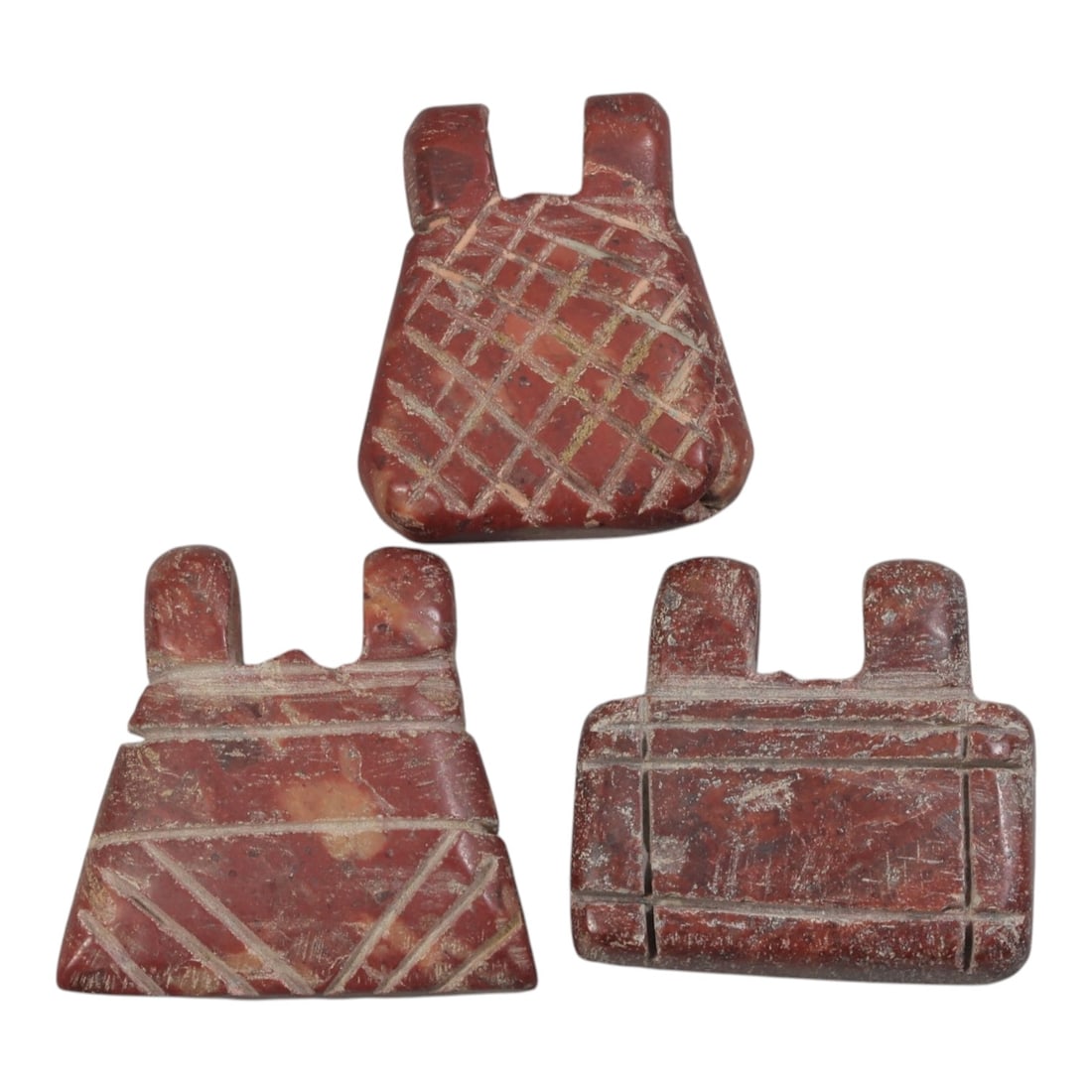 Lot of 3 Islamic Period Red Stone Amulets, Circa Medieval Period, 74AE: The group comprises three carved red stone amulets of geometric forms, characteristic of Islamic-period talismanic objects. All are worked from red stone with natural patination, surface wear, and inc
