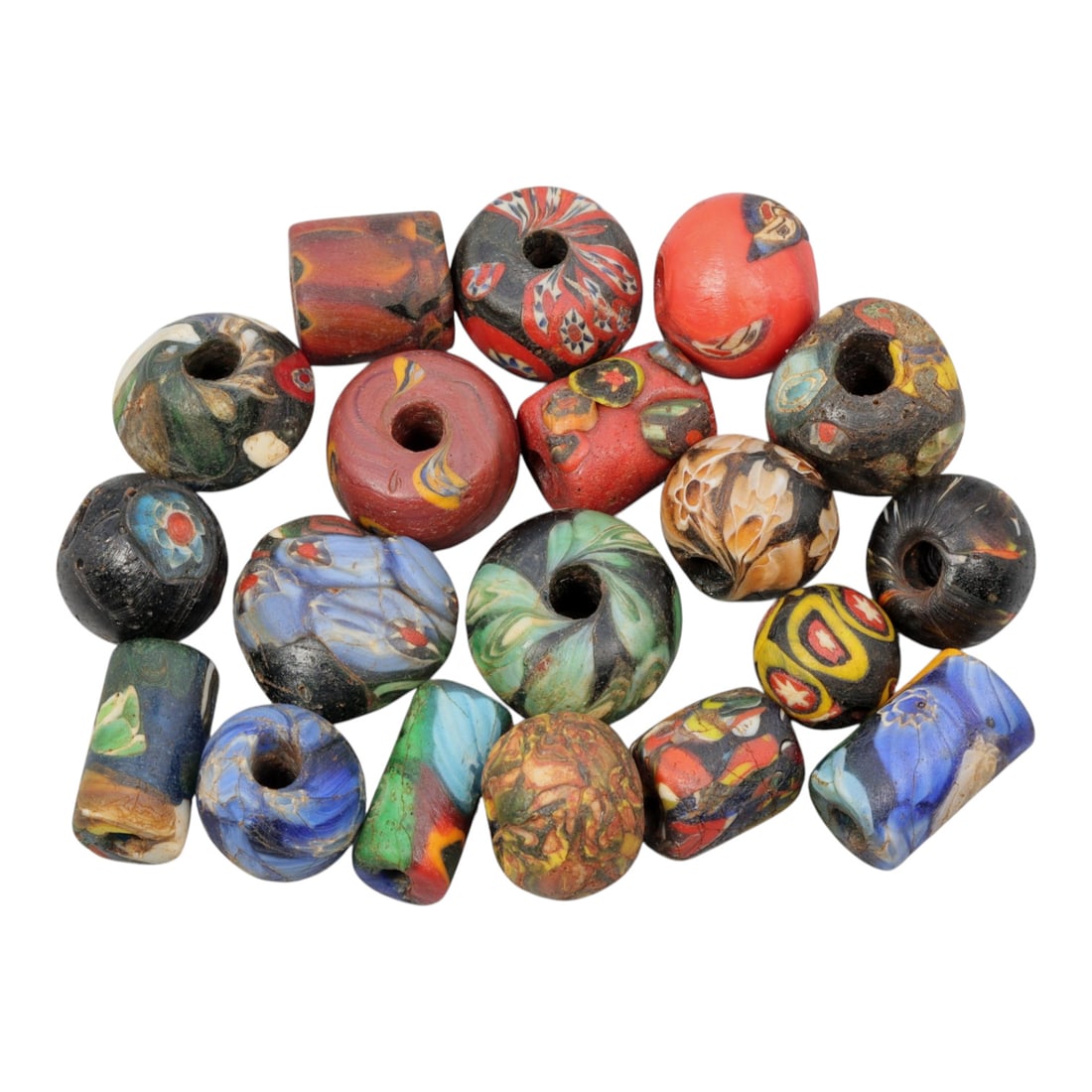A Lot of 19 Antique/ Vintage Artisan Glass Trade Beads, 27WM: A diverse collection of 19 glass trade beads, varying in form from spherical, barrel, and cylindrical to faceted shapes, all with central perforations for threading. The beads feature intricate mosaic