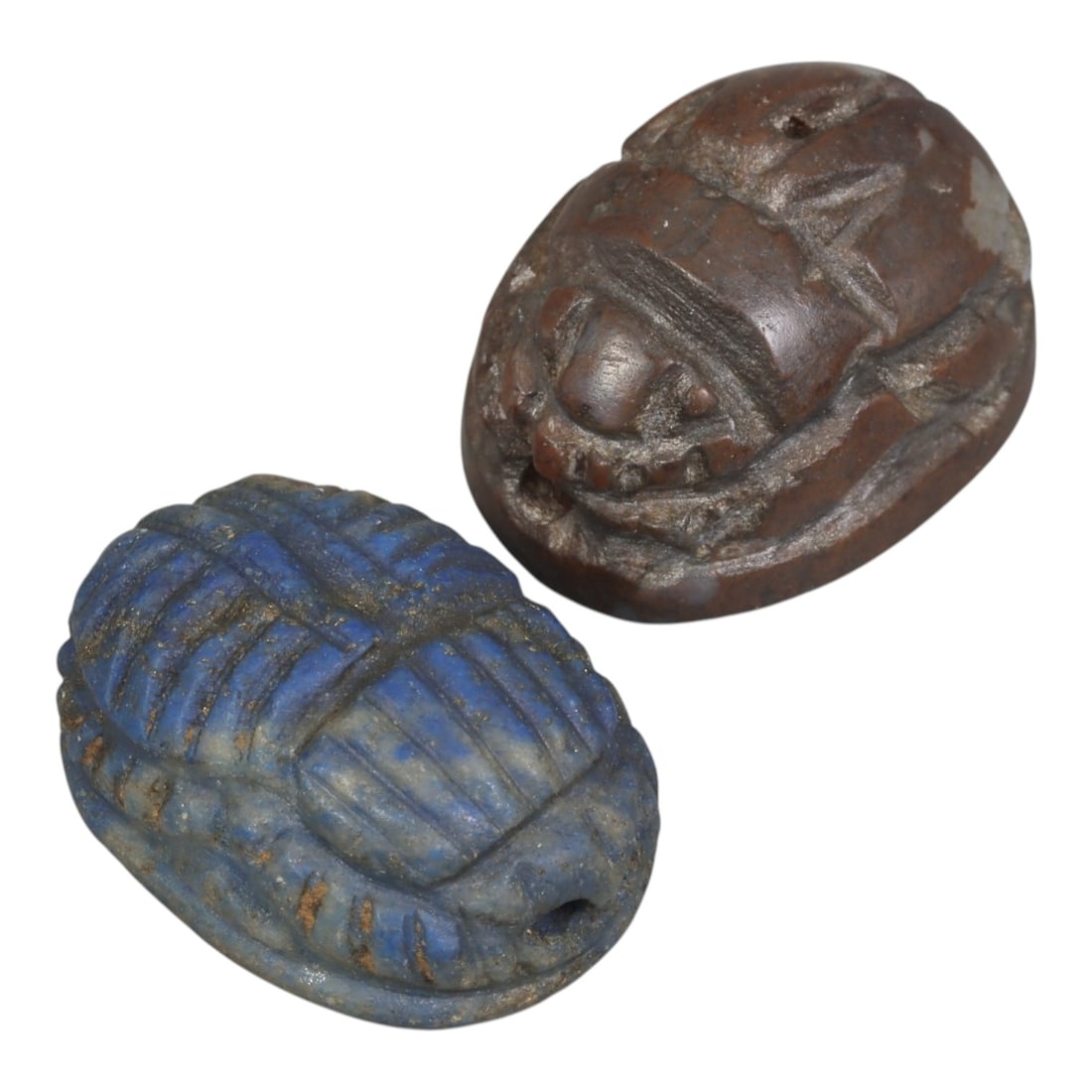 Lot of 2 Ancient Coptic Egyptian Scarabs, Circa Roman to Coptic Era, 92AE: The group comprises two scarab amulets, one carved from lapis lazuli and one from dark brown stone. The lapis lazuli example is rendered with deeply incised lines defining the segmented carapace, elyt