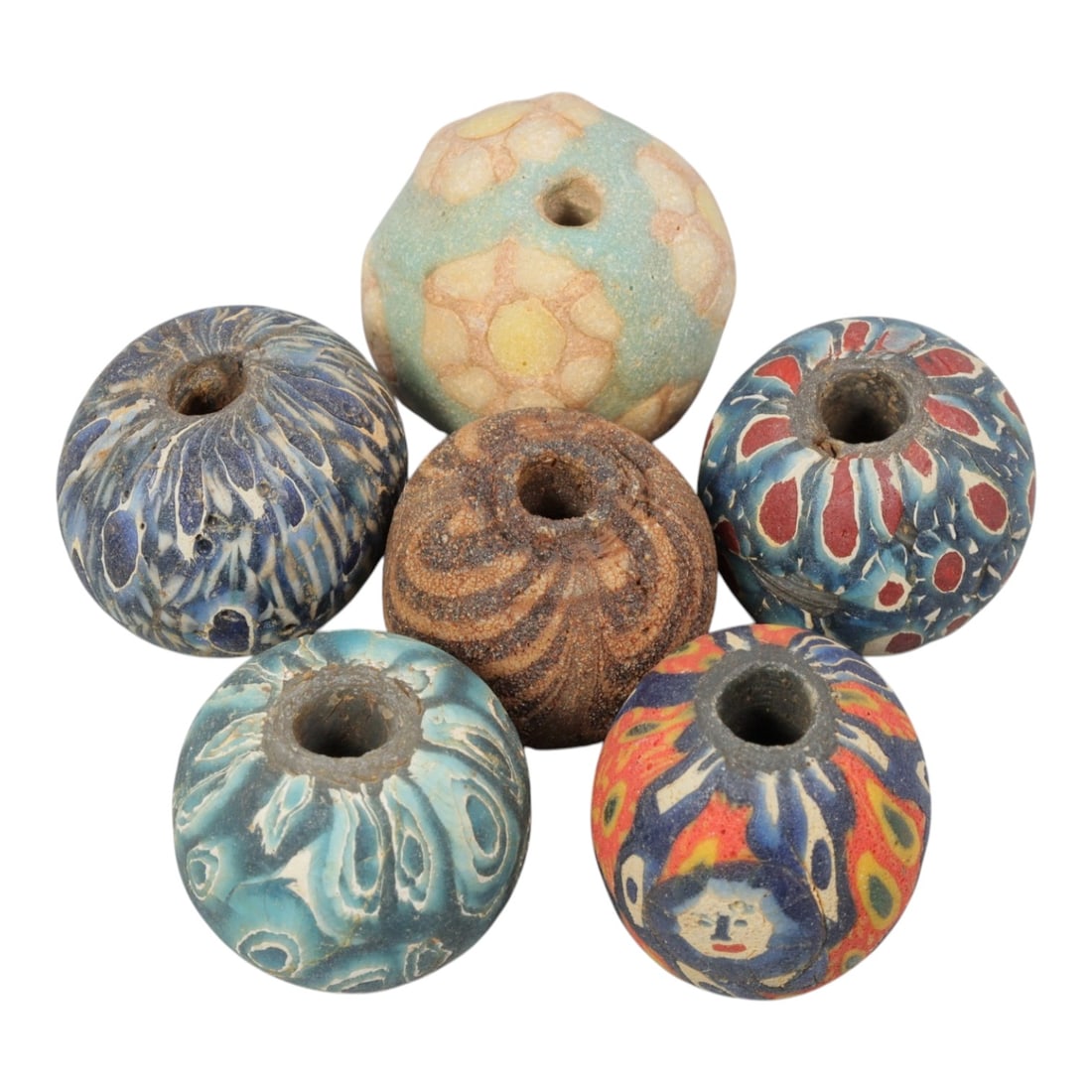 Lot of 6 Ancient to Antique Glass Beads, Circa 1st Millennium BCE to Islamic Period, 71AD: Comprising six beads of approximately 2 cm (3/4 in.), representing diverse ancient and antique glassworking traditions. The beads display a rich variety of techniques and designs, including floral mos