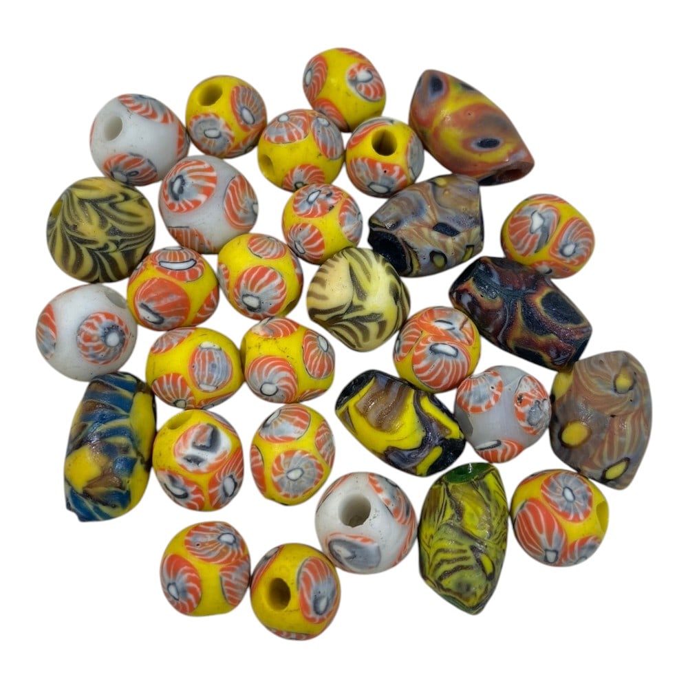 A Lot of 29 Vintage Mosaic Glass Beads, 85AA: The group comprises twenty-nine beads of varying shapes, including spherical, barrel, and cylindrical forms, crafted from polychrome mosaic glass. The majority feature repeating circular eye motifs in
