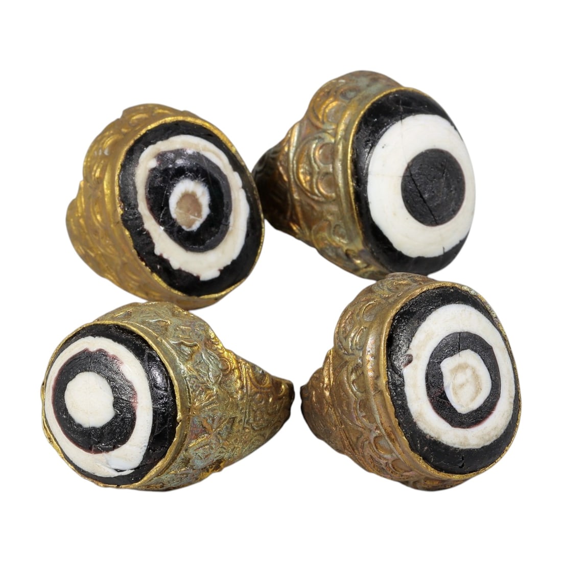 Lot of 4 Antique Qajar Period Gilt Evil Eye Rings, 11AD: A collection of four antique gilt-metal rings from the Qajar period (19th century), each set with a layered black-and-white "evil eye" stone cabochon. The stones feature concentric bullseye patterns, 
