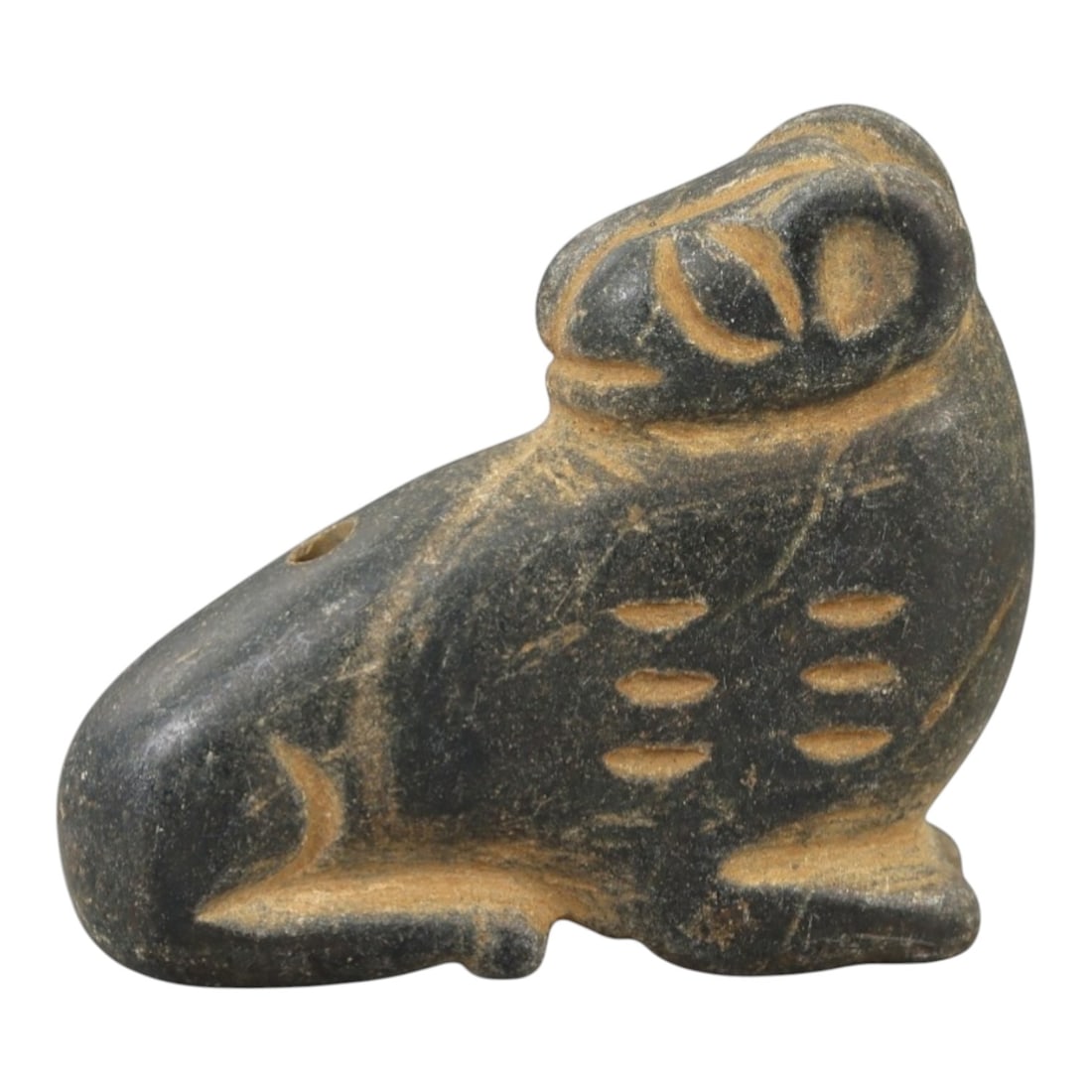 Ancient Stone Zoomorphic Amulet - Near Eastern Animal Figure, 57AM: This amulet is carved from dark grey stone, depicting a stylized quadrupedal animal in a seated posture, with incised linear and oval detailing defining the facial features, ears, and body patterns. T