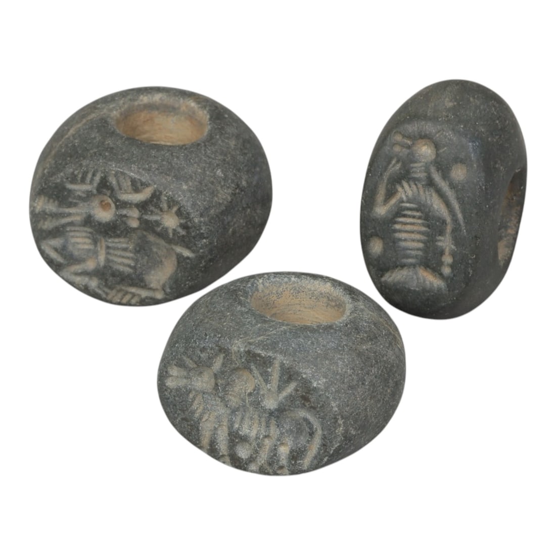 Lot of 3 Sasanian Stone Stamp Seals, Circa 3rd-7th Century CE, 5AG: Comprising three seals carved from dark grey stone with natural patina and surface wear consistent with ancient use. Each seal is of rounded disc or oval form with a central perforation for suspension