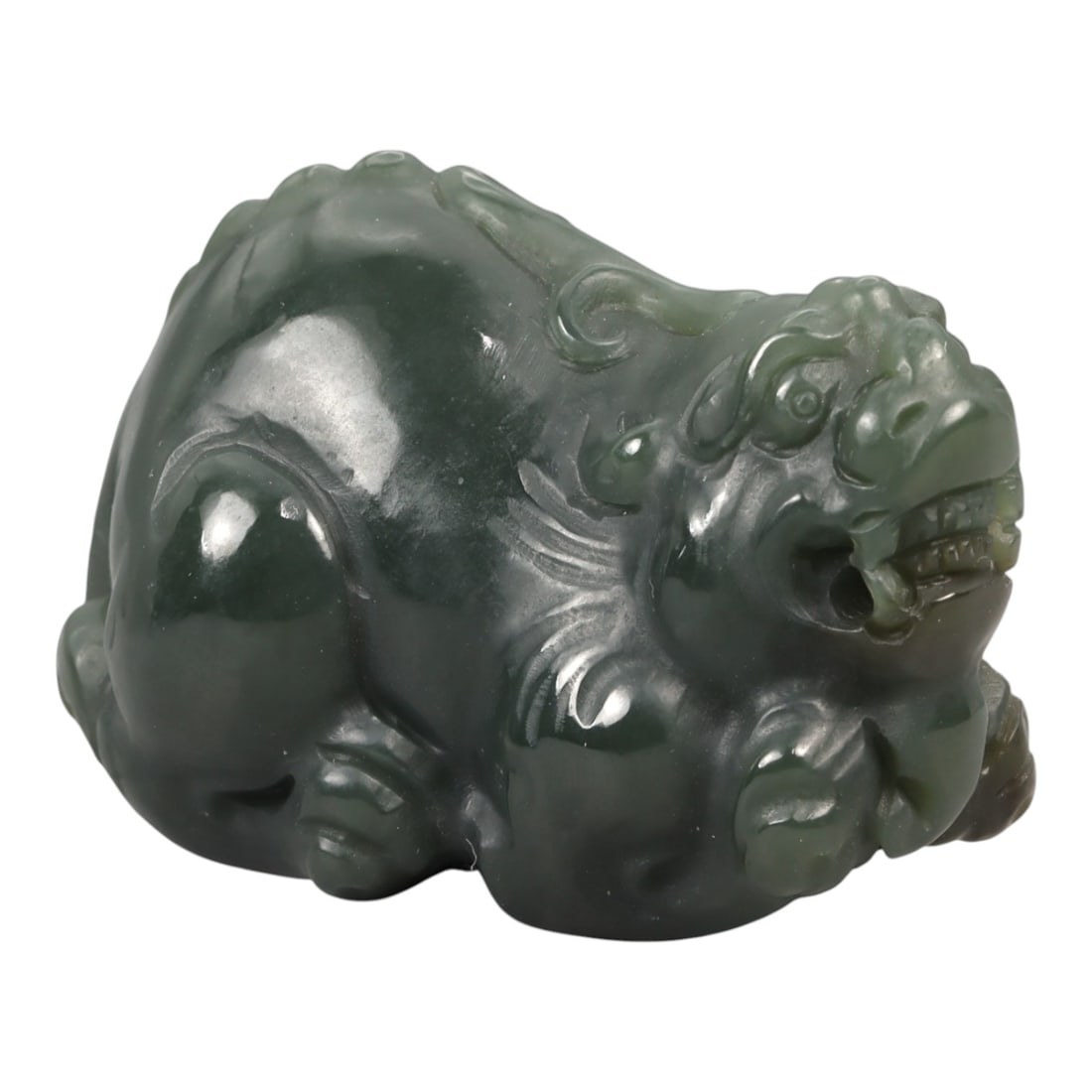 A Chinese Nephrite Jade Mythical Beast Figure, 20th Century, 64YA: Carved from dark green nephrite jade with areas of deeper saturation and soft translucency, the figure represents a recumbent mythical beast shown in a compact, crouching posture. The head is rendered