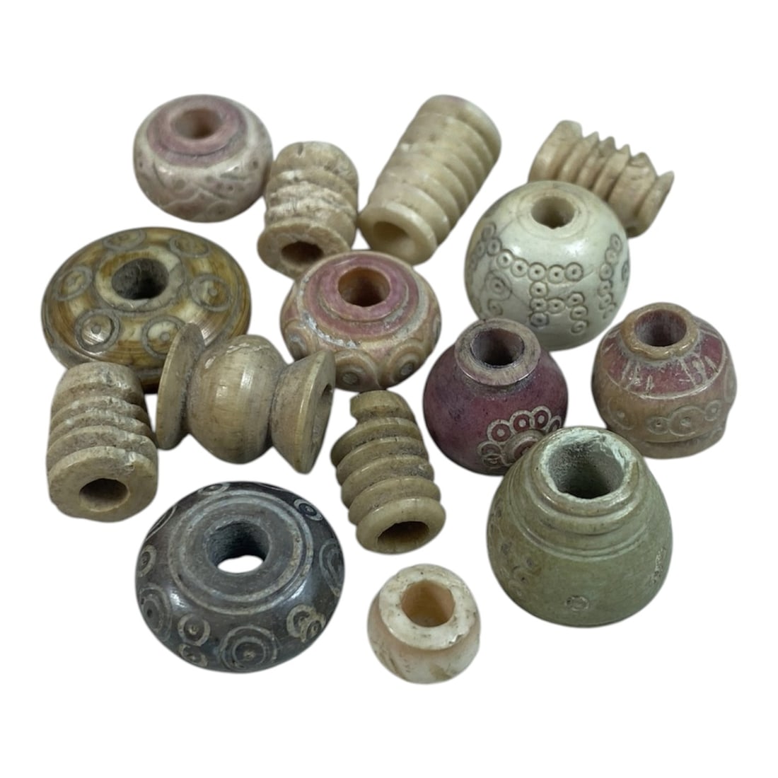 A Lot of 15 Ancient Silk Road Bone Spindle Whorls, 57AB: The group comprises 15 ancient bone spindle whorls, exhibiting natural aged tones including cream, beige, and grey with traces of pigment and surface patina consistent with artifacts from the Silk Roa
