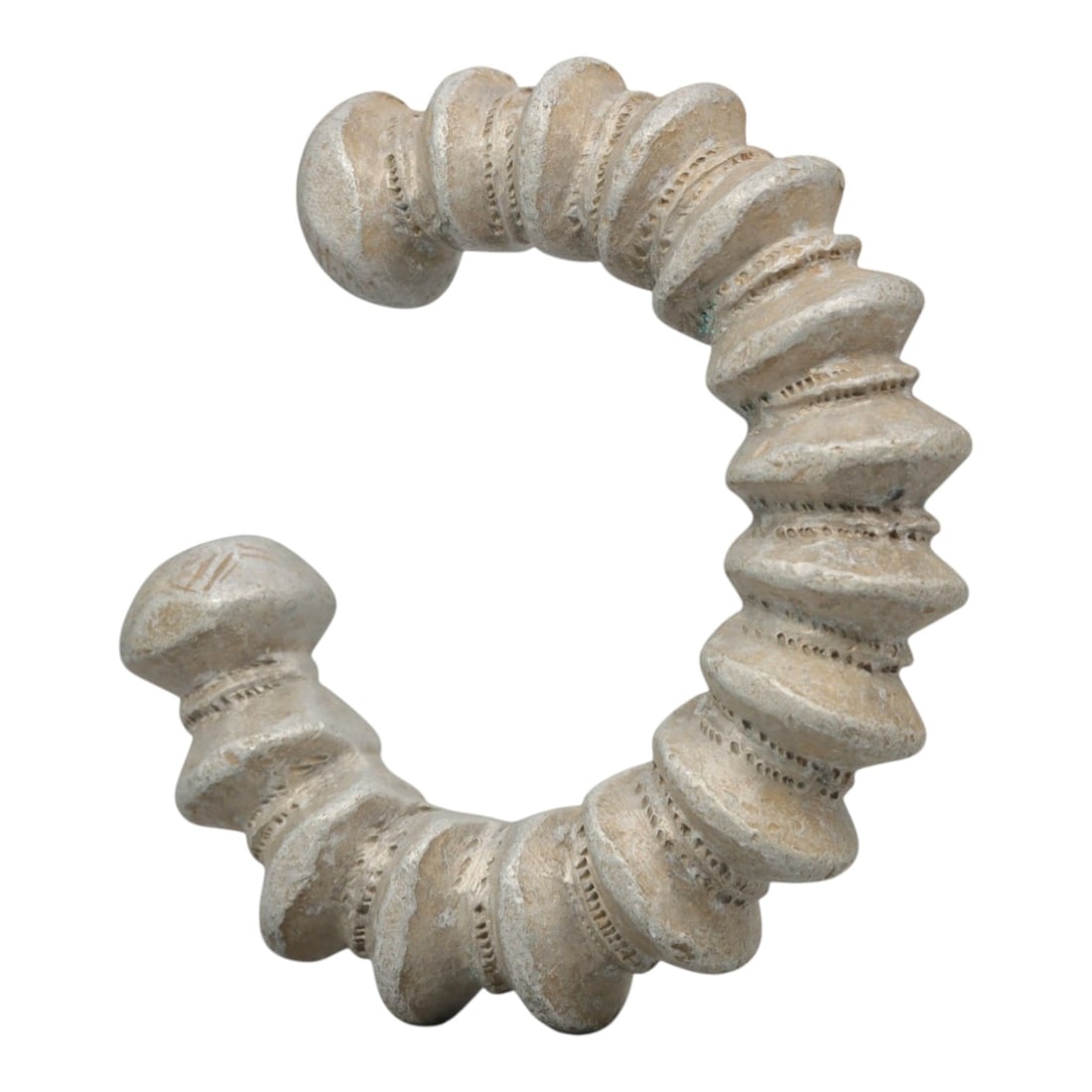 An African Silvered Aluminium Bracelet, 20th Century, 97FT: Formed from silvered aluminium, the bracelet is constructed as an open C-shape, composed of a series of stacked, disc-like segments separated by fine, incised linear bands. The terminals are rounded a
