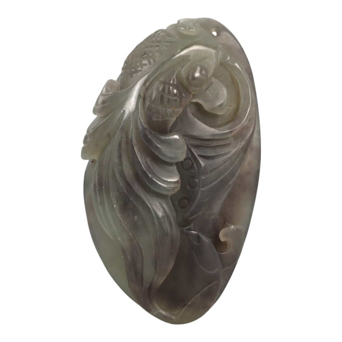 A Chinese Nephrite Jade Fish Carving, 20th Century, 56YA: Carved from pale gray-green nephrite jade with areas of darker inclusions and subtle translucency, the object is modeled in the form of a fish shown in dynamic profile. The body is articulated with fl