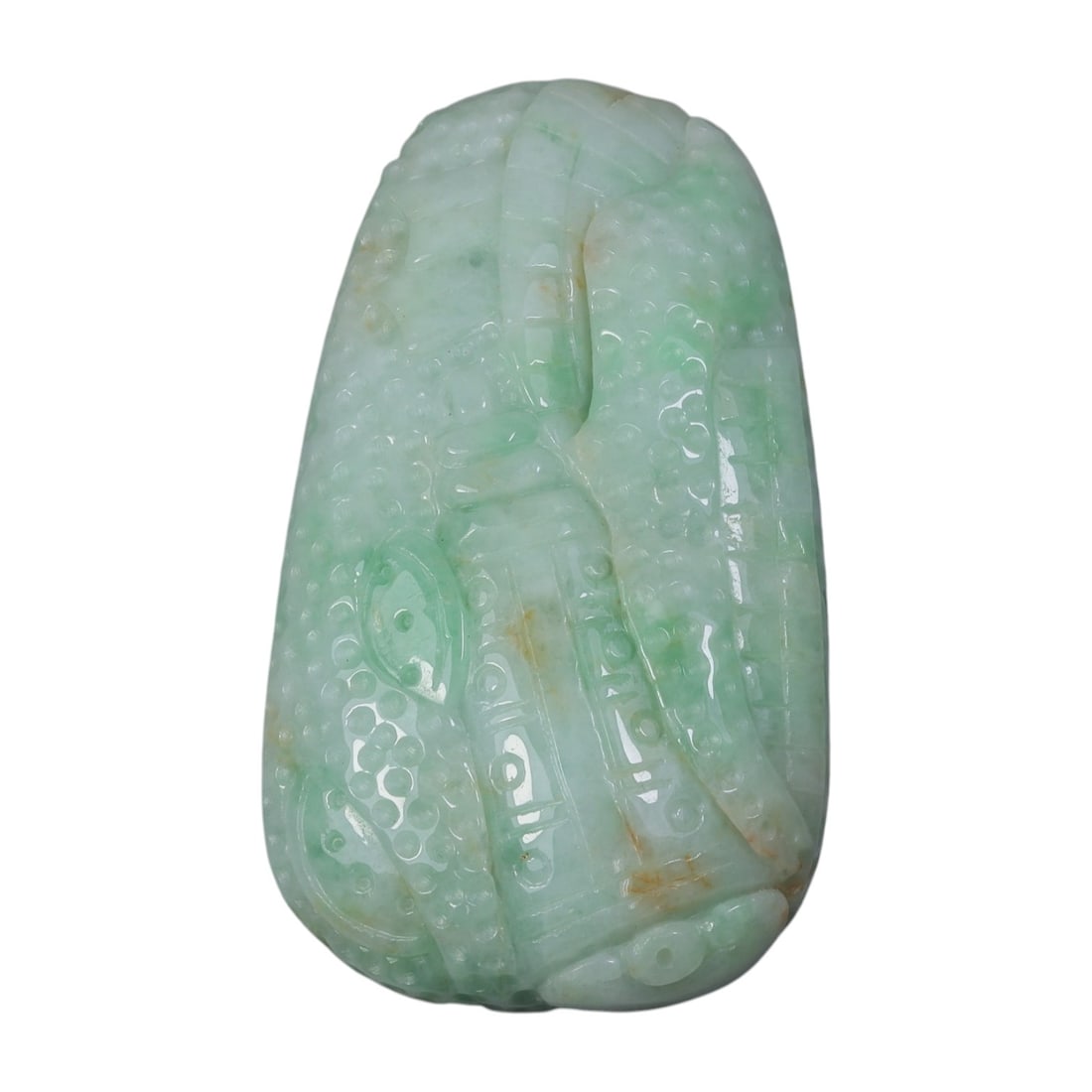 An Antique Oriental Chinese Jadeite Jade Pendant, 37AG: Carved from pale green jadeite with scattered russet inclusions, the pendant features an irregular teardrop form. The surface is rendered in high relief with overlapping archaic-style motifs, includin