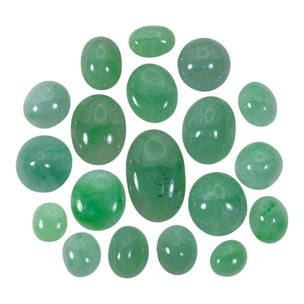 A Lot of 19 Natural Apple Green Jadeite Jade Cabochons, 70.56ct Total, 31AB: This collection features 19 polished jadeite jade cabochons in soft apple green hues, ranging from pale translucent tones to richer saturated shades. The stones are primarily oval and round-shaped, wi