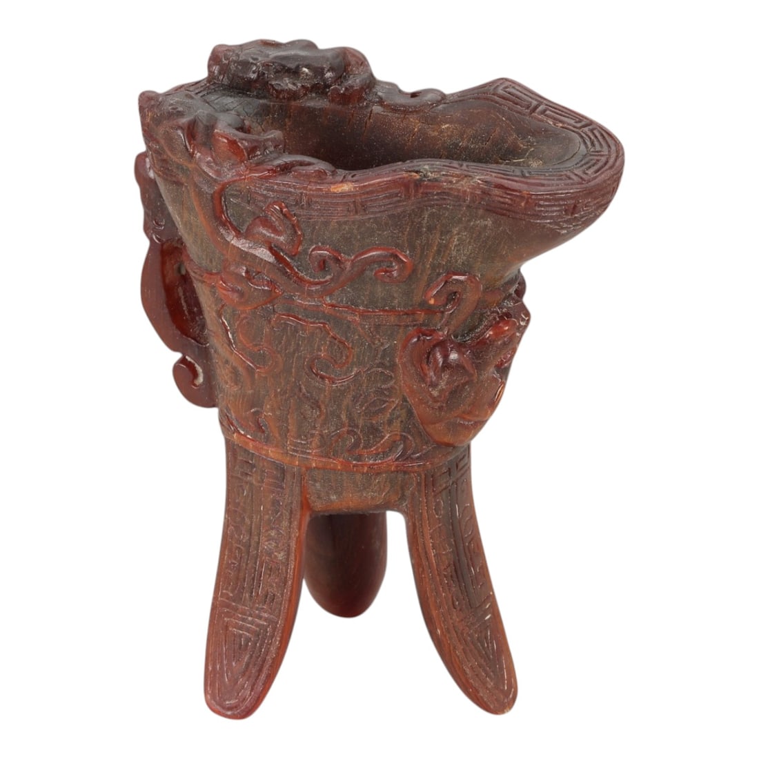 A Chinese Horn Libation Cup, Archaistic Style, 20th Century, 48FG: Carved from dark brown horn with natural tonal variation, the vessel is formed in the shape of an archaistic ritual cup supported on three tapering legs. The body flares upward to an irregular oval ri
