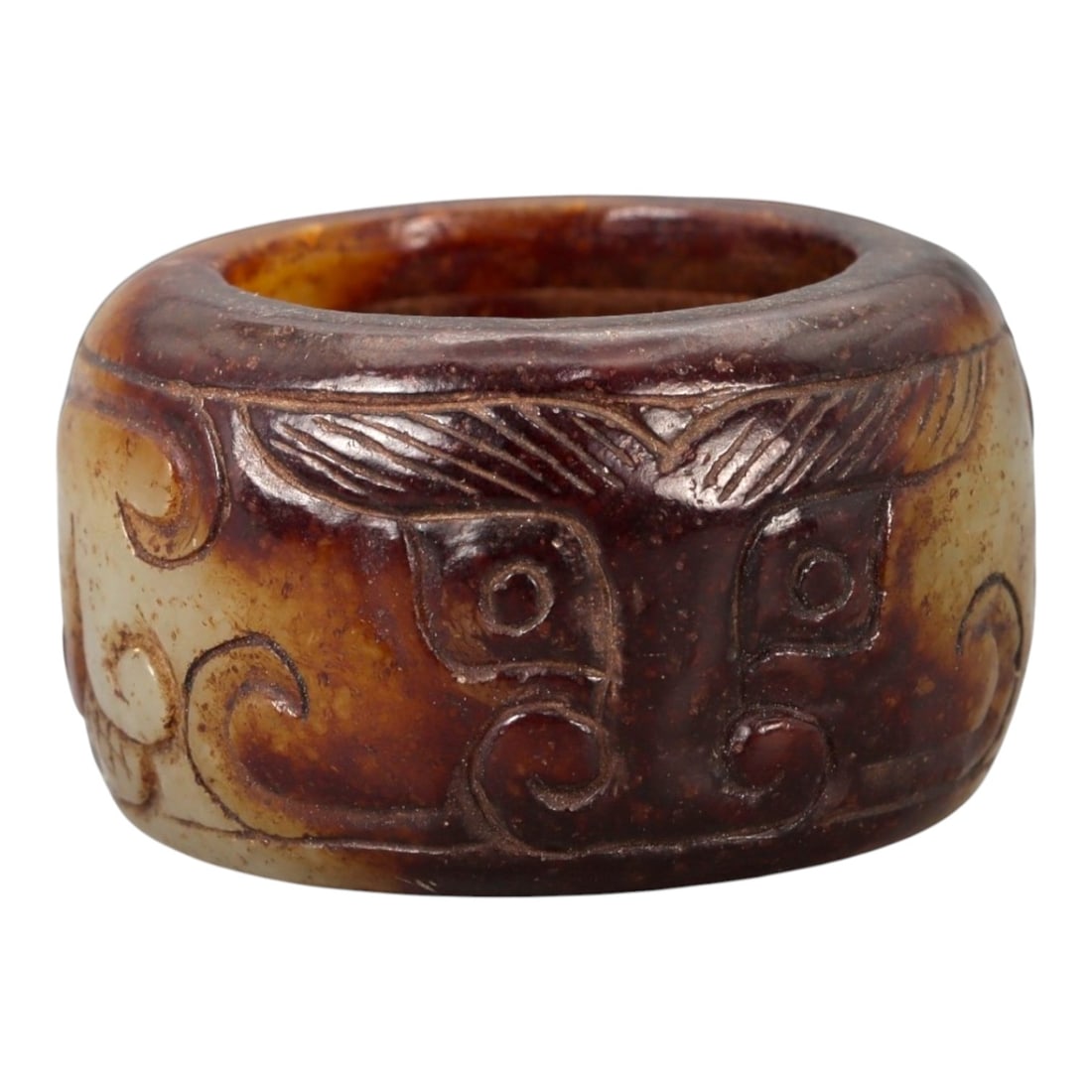 A Chinese Nephrite Jade Ring, 20th Century, 13FA: Carved from mottled brown and pale celadon nephrite jade with natural color variation and areas of translucency, the ring is formed with a thick circular profile and a wide band. The exterior surface 
