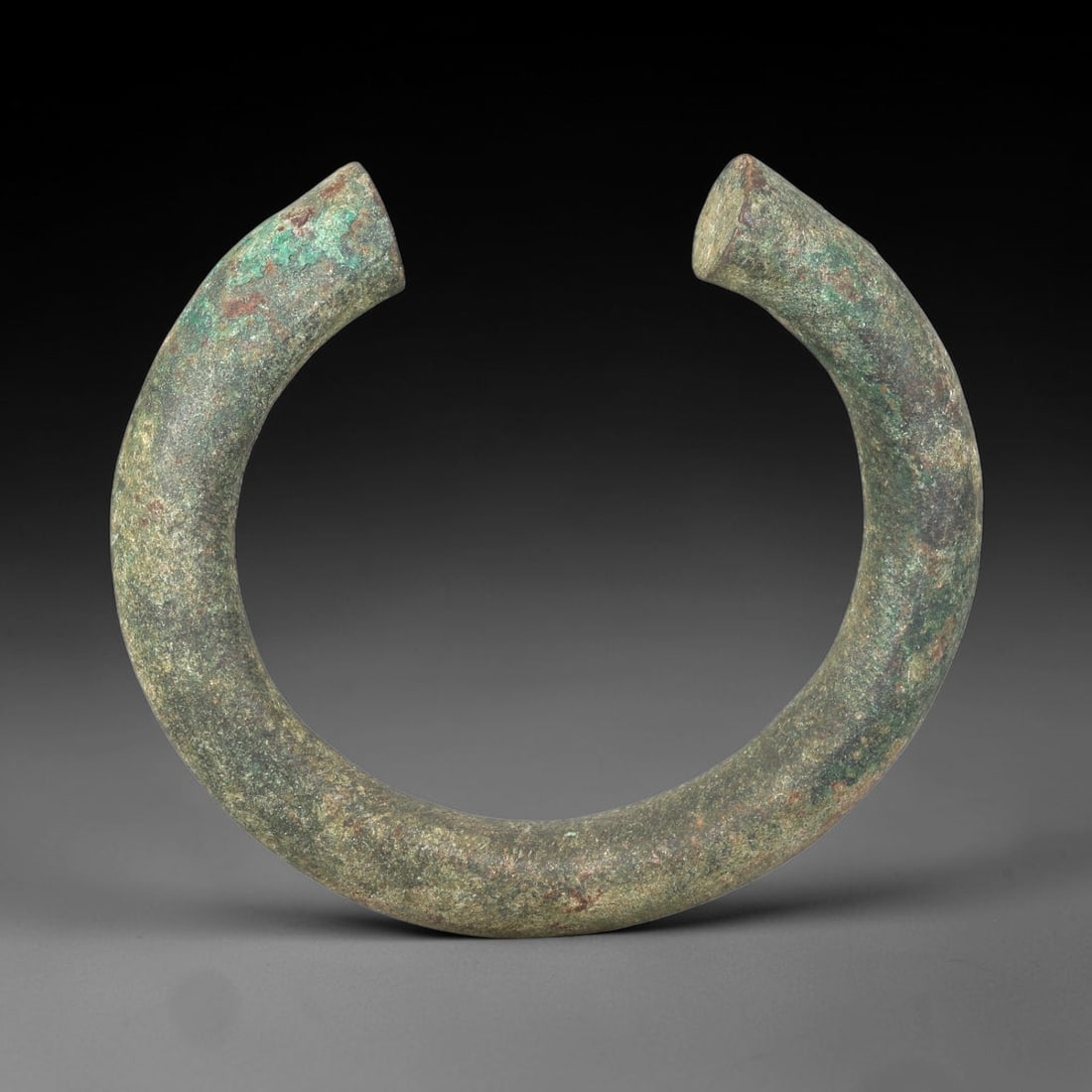 Ancient Bronze Bracelet - Roman Open Cuff Bangle, 90BN: An open cuff bracelet crafted from thick cast bronze, with rounded cross-section and squared, flat terminals. The robust construction is characteristic of Roman provincial jewelry, designed for durabi