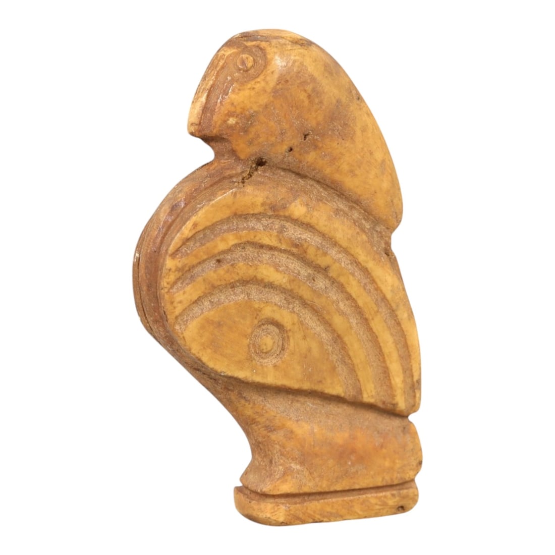 Ancient Bone Bird Amulet - Near Eastern Figurine, 84AL: Carved from tan bone, this amulet depicts a stylized avian form with a rounded head, incised eye, and curved beak. The body features concentric incised linear patterns creating a layered, feather-like