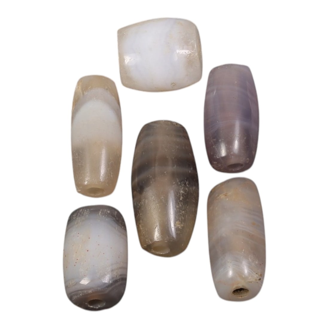 Lot of 6 Ancient to Antique Period Himalayan Silk Road Banded Agate Beads, 66AD: A group of six beads carved from banded agate with varying translucency, natural shades of grey, white, and subtle purple tones, with distinct linear and concentric banding patterns visible throughout
