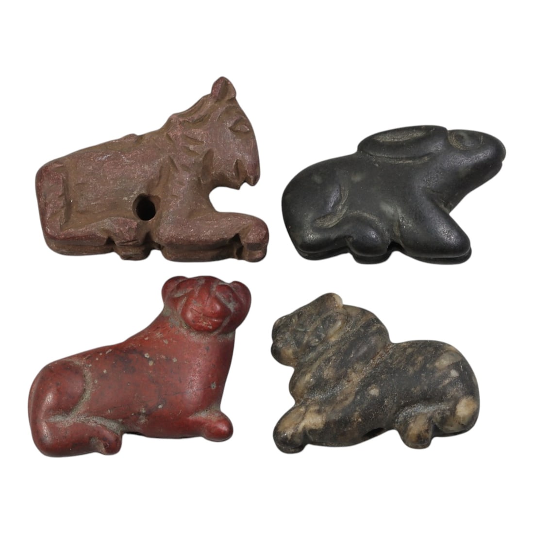 Lot of 4 Ancient Bactrian Zoomorphic Stone Amulets, Circa 3rd-1st Millennium BCE, 59AE: The group comprises four carved zoomorphic amulets depicting recumbent animals, including a feline, hare, and other stylized quadrupeds, characteristic of ancient Bactrian art. The pieces are worked i
