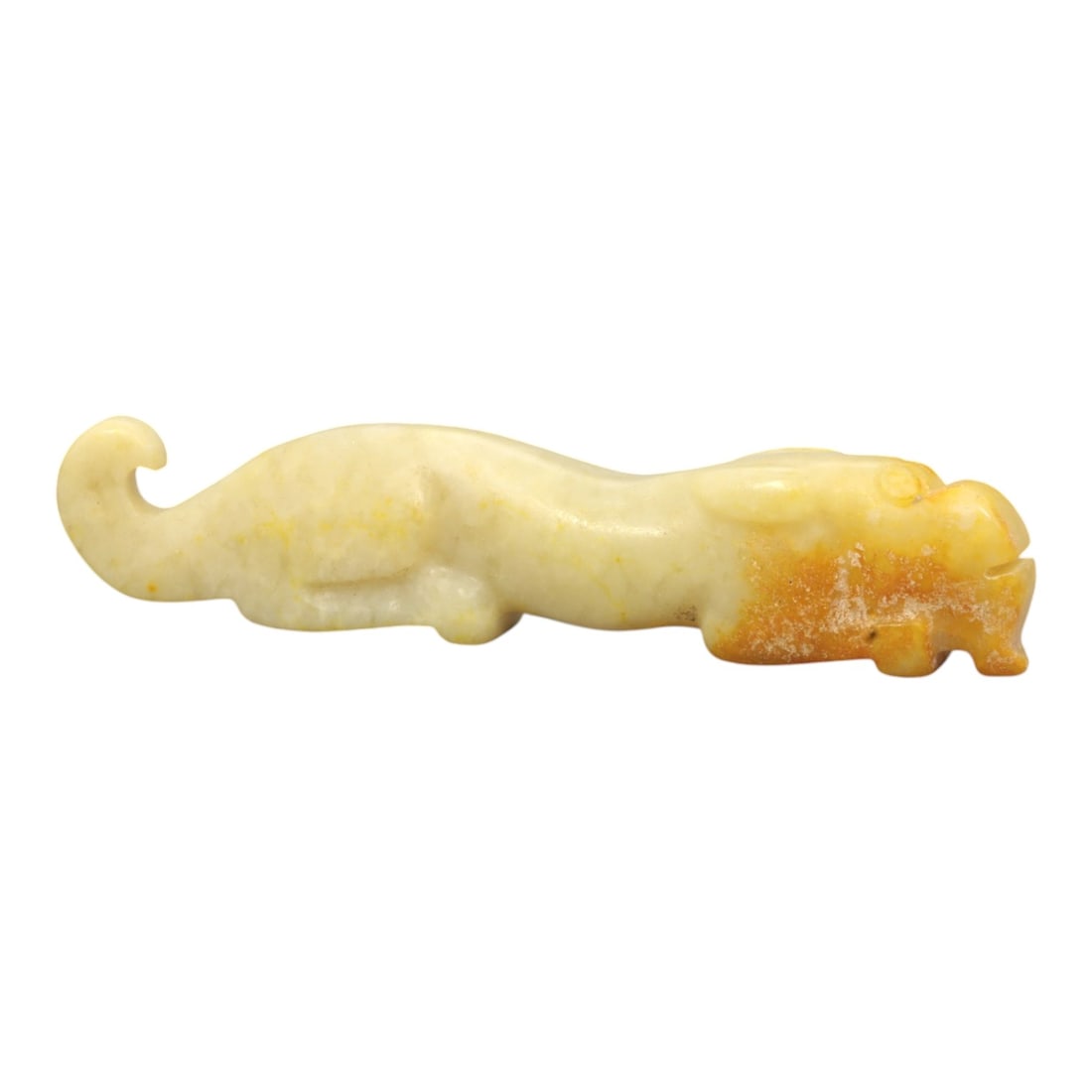 A Chinese Hetian Jade Zoomorphic Ornament, 20th Century, 57FH: Carved from pale creamy-white Hetian jade with areas of natural yellow and russet staining concentrated toward the head, the ornament is worked as an elongated zoomorphic figure shown recumbent in pro
