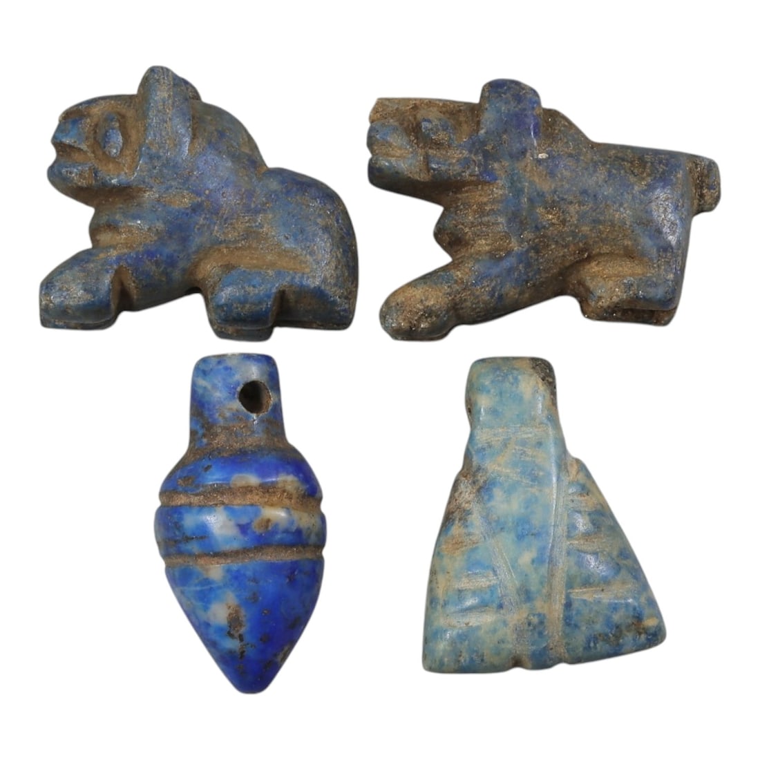 Lot of 4 Parthian Period Lapis Lazuli Amulets, Circa 3rd Century BCE - 3rd Century CE, 30AE: The group comprises four carved lapis lazuli amulets characteristic of Parthian art. The pieces include two zoomorphic recumbent quadruped figures, a bud/pomegranate-shaped pendant, and a stylized con