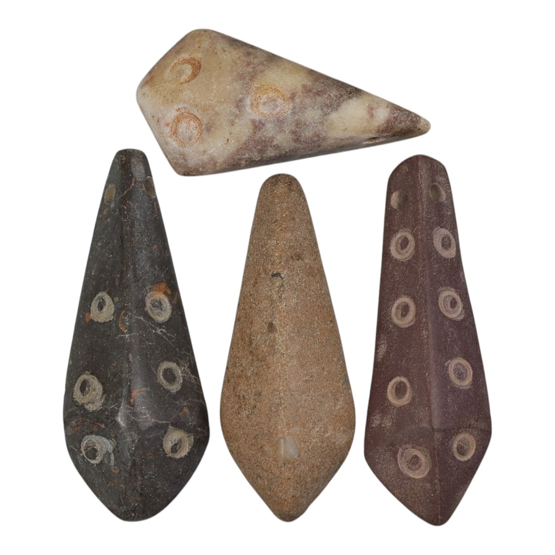 Lot of 4 Achaemenid Period Stone Amulets, Circa 5th-4th Century BCE, 49AE: The group comprises four carved stone amulets of elongated, tapering form, characteristic of the Achaemenid period. The pieces are worked in varied stone tones: mottled beige with purple veining, dark
