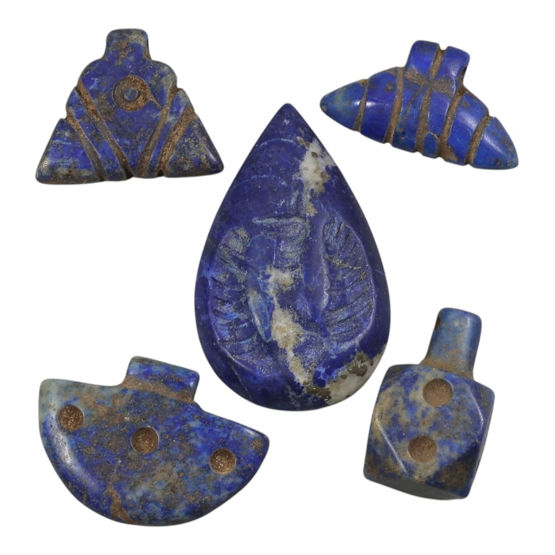 Lot of 5 Parthian Period Lapis Lazuli Amulets, Circa 3rd Century BCE-3rd Century CE, 29AE: The group comprises five carved lapis lazuli amulets of varied forms, including a teardrop-shaped example with an incised bust, a triangular form with a circular motif, a segmented conical pendant, a 