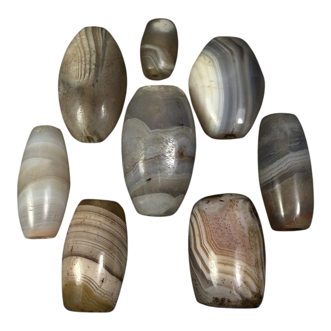 Lot of 8 Himalayan Banded Agate Beads, Ancient to Antique Period, 19AH: A group of eight beads crafted from banded agate, displaying natural tonal variations including translucent grey, white, cream, and subtle brownish hues, with characteristic concentric, linear, and wa
