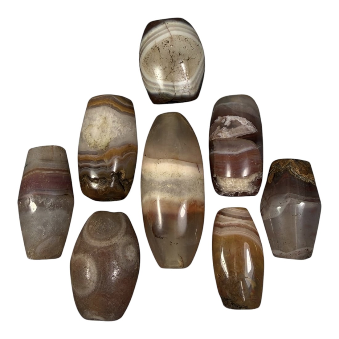 Lot of 8 Himalayan Banded Agate Beads, Ancient to Antique Period, 98AG: A group of eight beads crafted from banded agate, displaying natural variations in tone including translucent grey, reddish-brown, yellow, and cream hues, with characteristic concentric, linear, and w