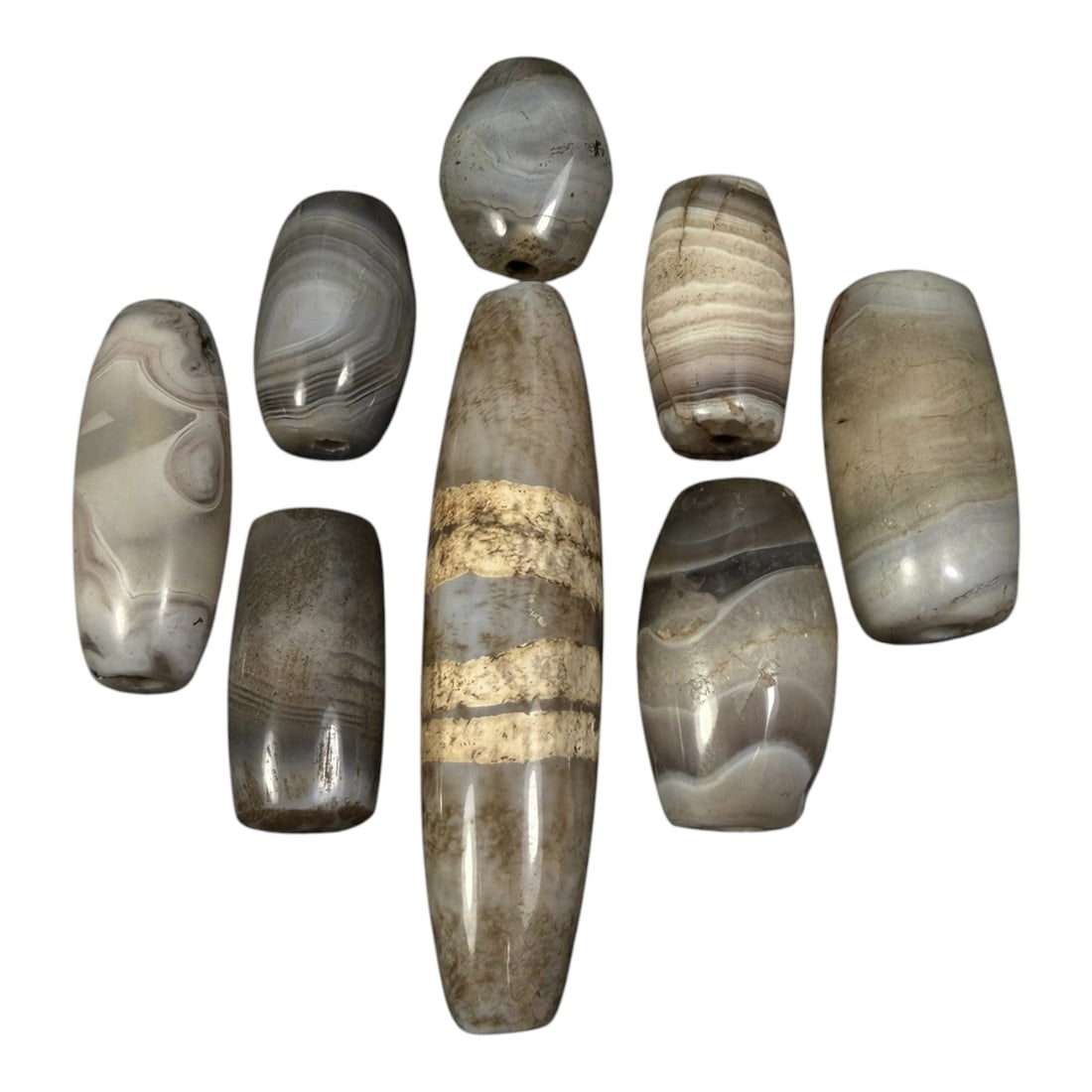 Lot of 8 Himalayan Banded Agate Beads, Ancient to Antique Period, 20AH: A group of eight beads crafted from banded agate, displaying natural tonal variations including translucent grey, white, and muted brown hues, with characteristic concentric, linear, and wavy banding 