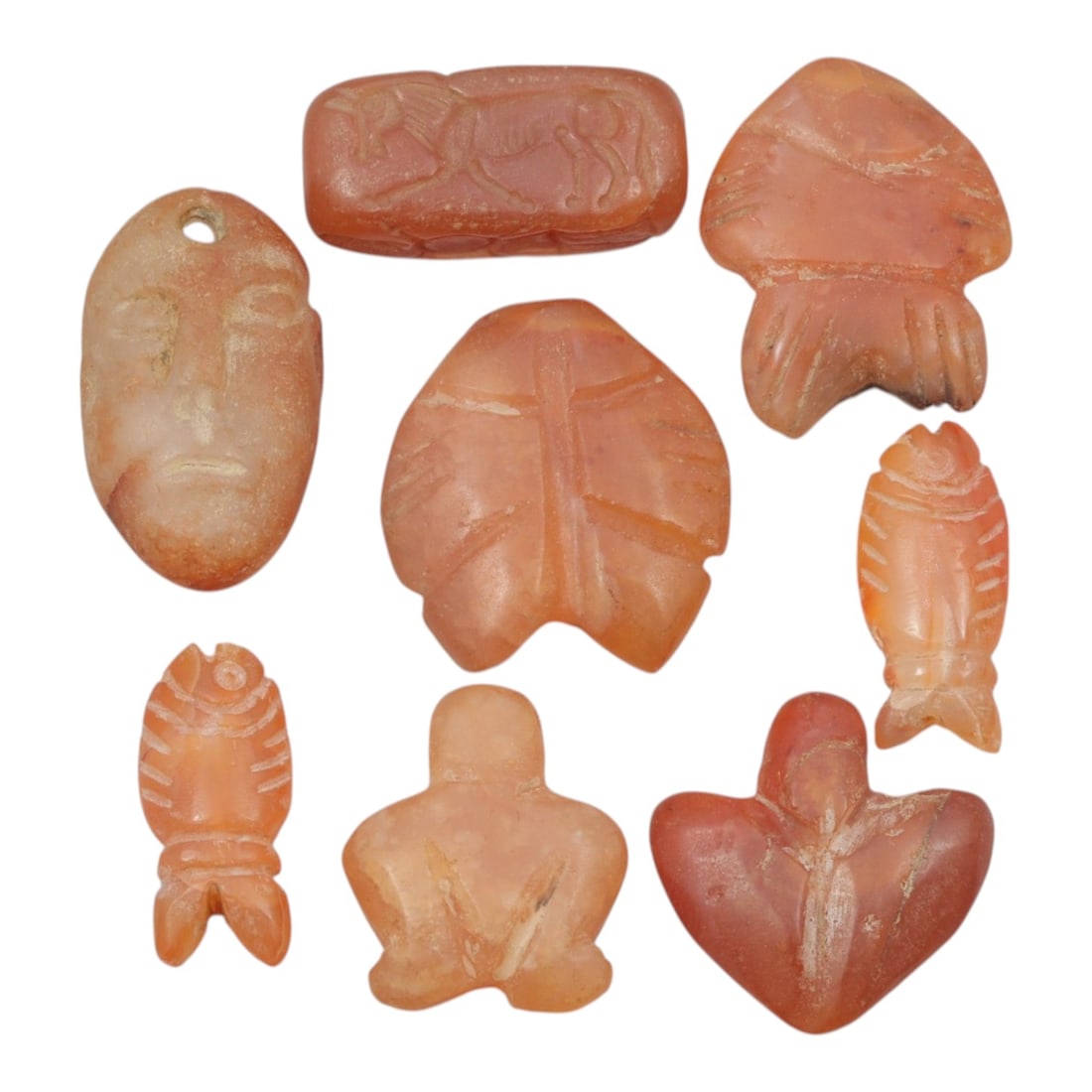 Lot of 8 Ancient Coptic Egyptian Carnelian Amulets, Circa Roman to Coptic Era, 60WT: Carved from carnelian in warm orange-red hues, the group consists of eight amulets of varying forms. The set includes stylized fish, leaf-shaped pendants, a human face pendant with suspension hole, a 
