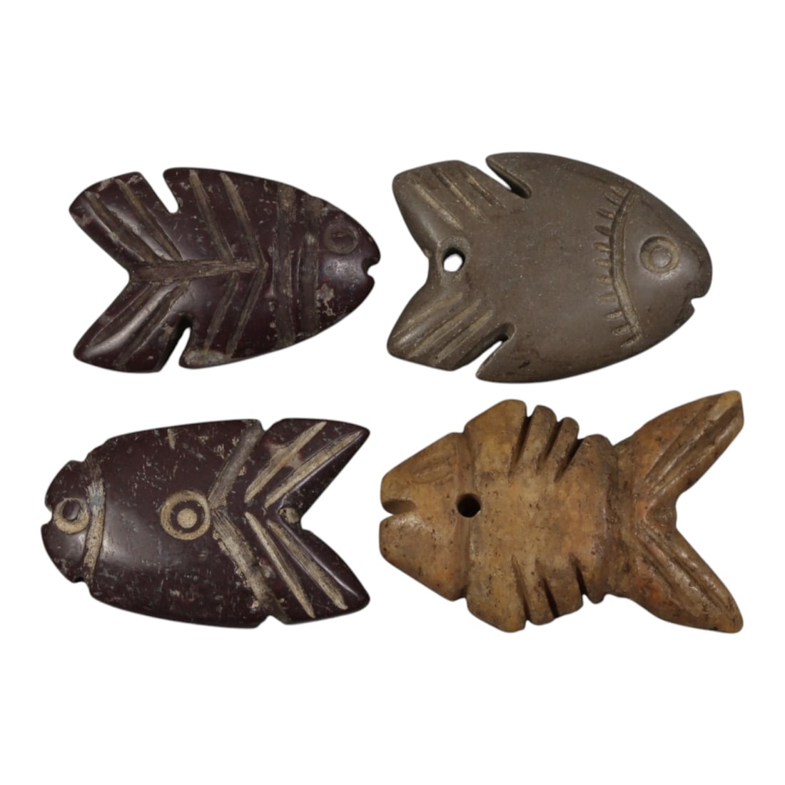 Lot of 4 Ancient Coptic Egyptian Stone Fish Amulets, Circa Roman to Coptic Era, 86WP: Carved from various stones, including dark brown, grey, and light tan varieties, the group consists of four flat fish-shaped amulets. Each piece features simplified incised detailing, including circul