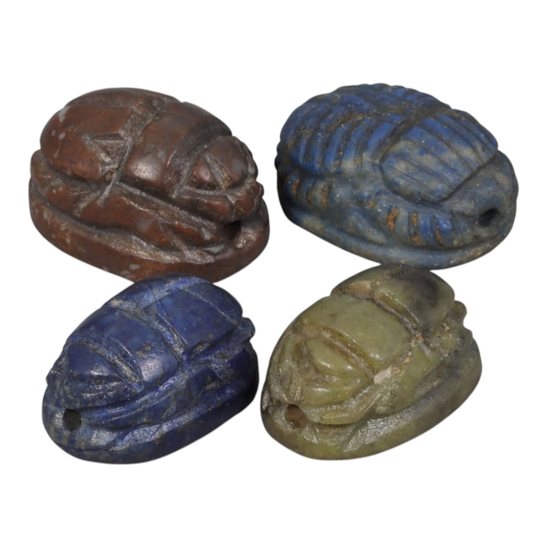 Lot of 4 Ancient Coptic Egyptian Multi-Stone Scarab Amulets, Circa Roman to Coptic Era, 1AJ: Carved from diverse semi-precious and stone materials, including lapis lazuli (blue), reddish-brown stone, and greenish stone, the group consists of four distinct scarab amulets, ranging in size from 