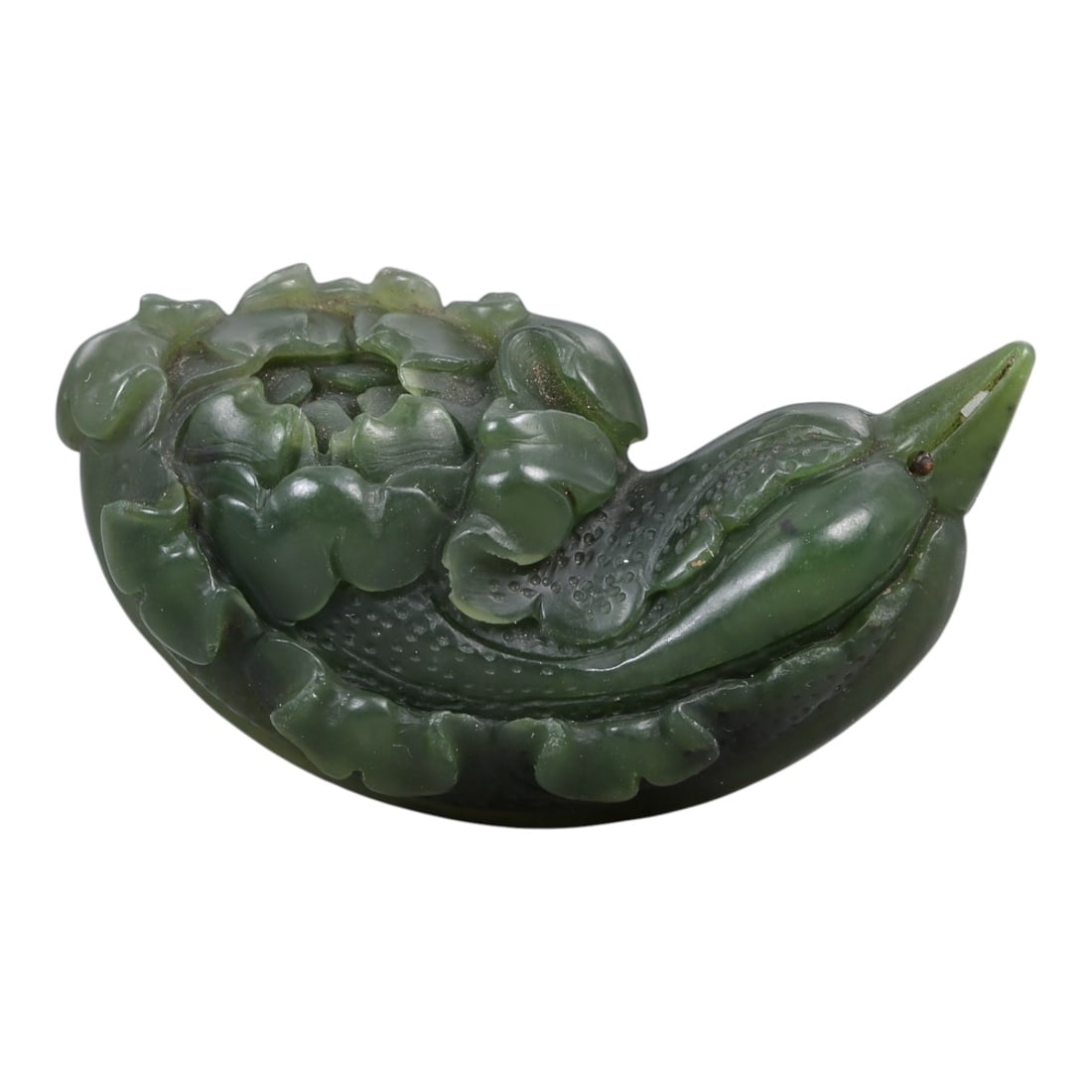 A Chinese Nephrite Jade Flower-Form Ornament, 20th Century, 31FA: Carved from dark green nephrite jade with lighter translucent areas and natural inclusions, the object is worked in the form of a flowering plant shown in low relief. The composition is horizontally o