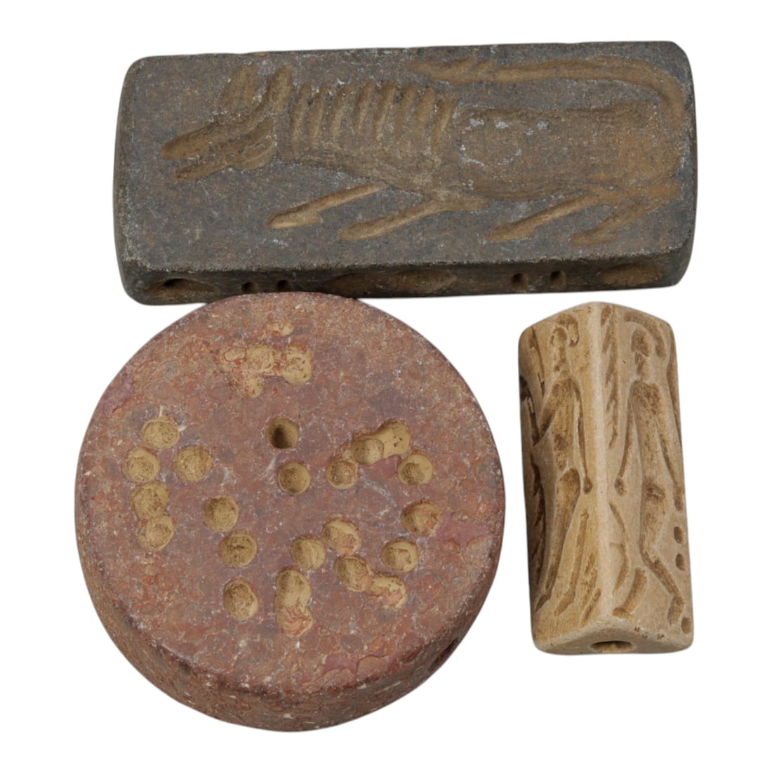 Lot of 3 Ancient Near Eastern Stone Seals / Artifacts, 8WT: A curated lot of three ancient Near Eastern-style stone artifacts, including a rectangular zoomorphic seal, a circular perforated disc, and a polygonal prism seal, all with natural patination and wear