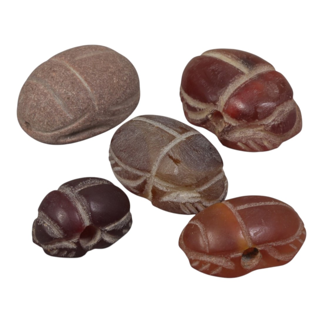 Lot of 5 Ancient Coptic Egyptian Multi-Stone Scarabs, Circa Roman to Coptic Era, 96WT: Carved from carnelian and earth-toned stone in shades of red, brown, and reddish-brown, the group consists of five distinct scarab amulets. Each piece features the characteristic scarab form with inci