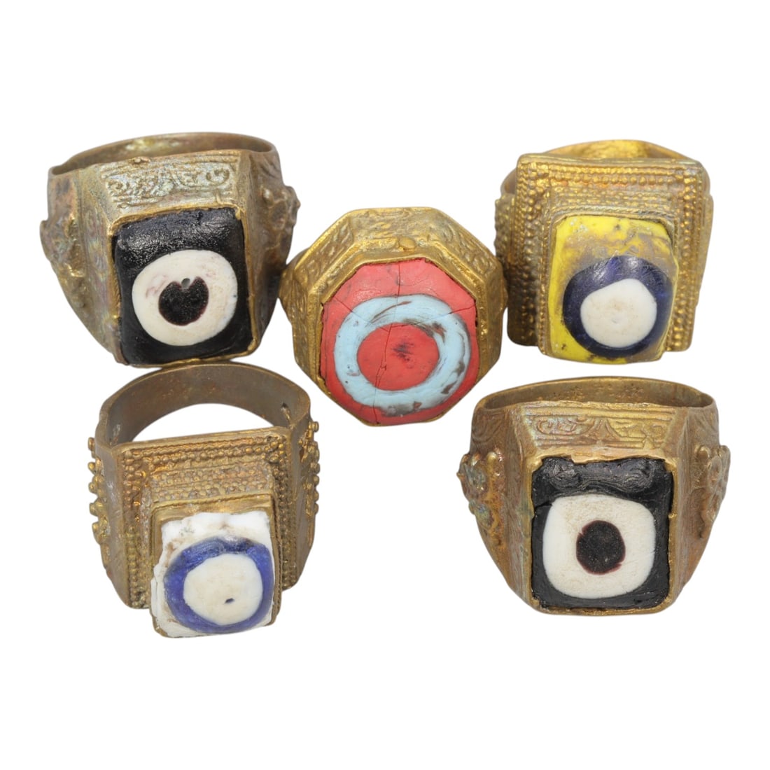 Lot of 5 Antique Qajar Period Gilt Evil Eye Glass Rings, 21AD: This is a collection of five gilt-metal rings dating to the Qajar period (19th century), each set with colorful "evil eye" glass cabochons. The set features varied designs and color palettes: two ring