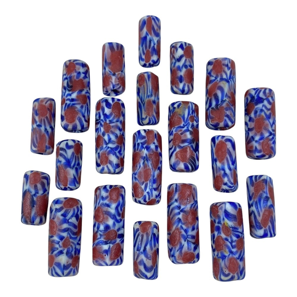 A Lot of 20 Vintage Cylindrical Millefiori Glass Beads, 78AA: This collection features 20 vintage glass beads, uniformly crafted into long cylindrical shapes. They showcase a striking millefiori-style pattern, with bold red and blue floral/abstract motifs set ag