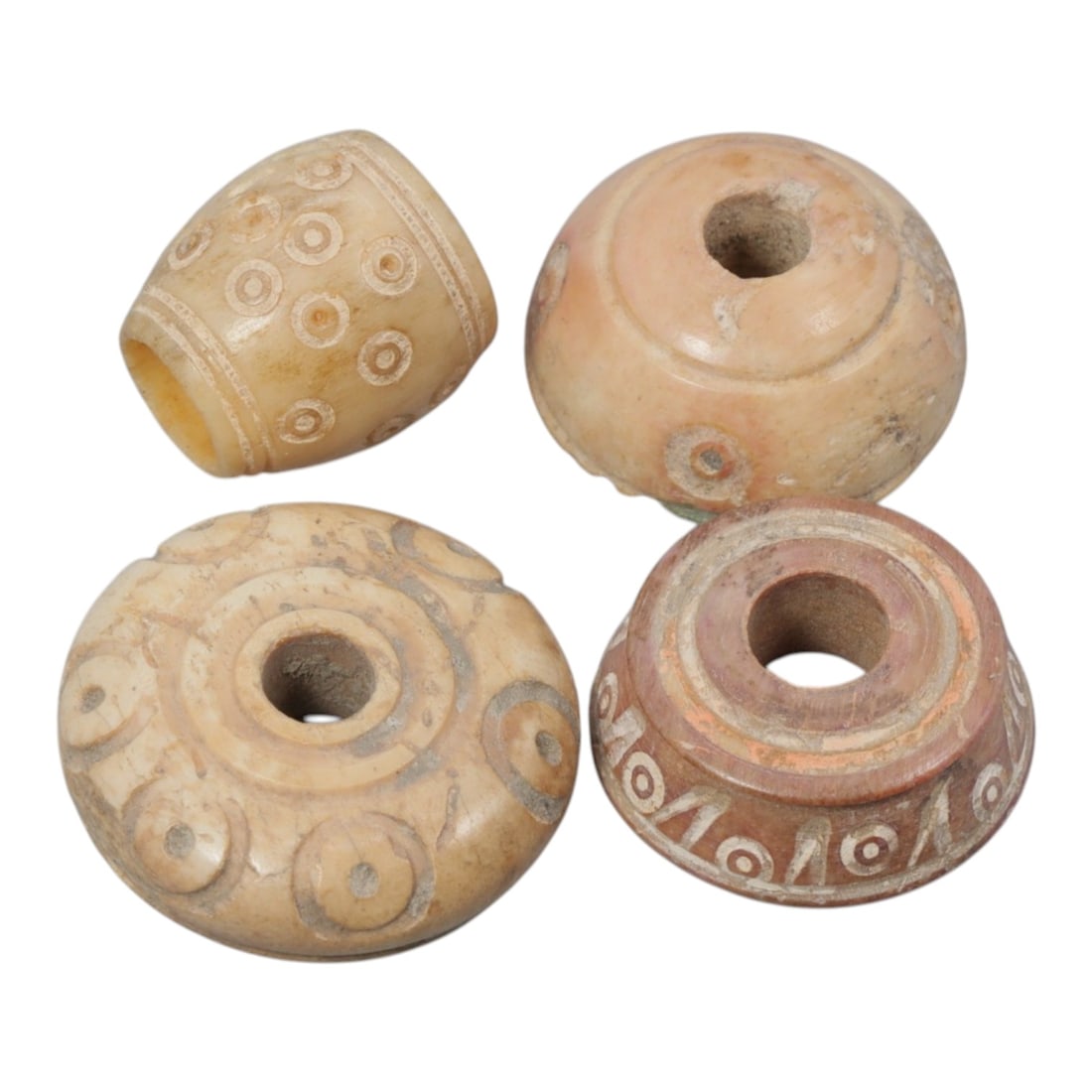 A Lot of 4 Ancient Silk Road Bone Spindle Whorls, 94WK: A collection of four ancient spindle whorls carved from bone, each with a central perforation for spindle mounting. The group includes examples with varied forms: barrel-shaped, spherical, and disc-sh