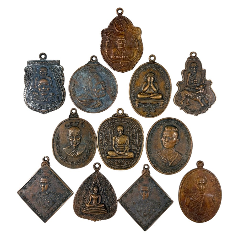 A Lot of 12 Vintage Thai Copper and Bronze Amulets, 48AA: Comprising 12 unmounted pendants ranging from 3.5 to 4 cm in height. The collection features a diverse array of cast metal amulets, including monastic portraits, revered royal figures, and sacred Budd