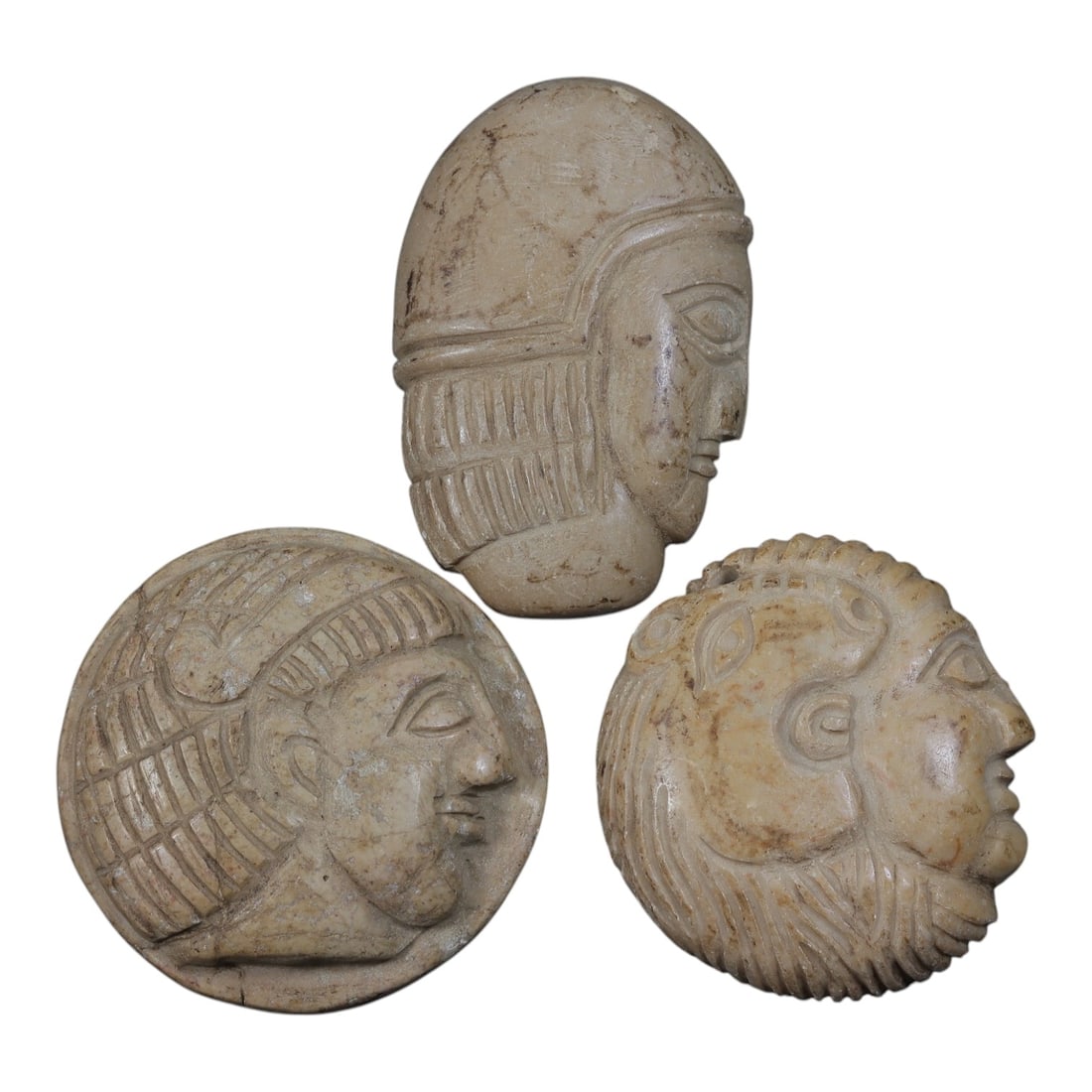 Lot of 3 Ancient Coptic Egyptian Steatite Face Beads / Amulets, Circa Roman to Coptic Era, 27AE: Comprising three finely carved steatite face amulets ranging from 4 cm to 5 cm, these pieces are characteristic of decorative and protective jewelry from the Coptic Egyptian period. Each is rendered i