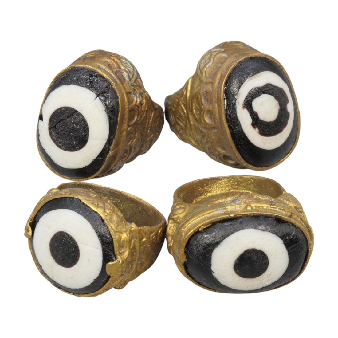 Lot of 4 Antique Qajar Period Gilt Evil Eye Glass Rings, 2AD: This is a collection of four gilt-metal rings from the Qajar period (19th century), each set with a classic black-and-white "evil eye" glass cabochon. The stones feature concentric bullseye patterns, 