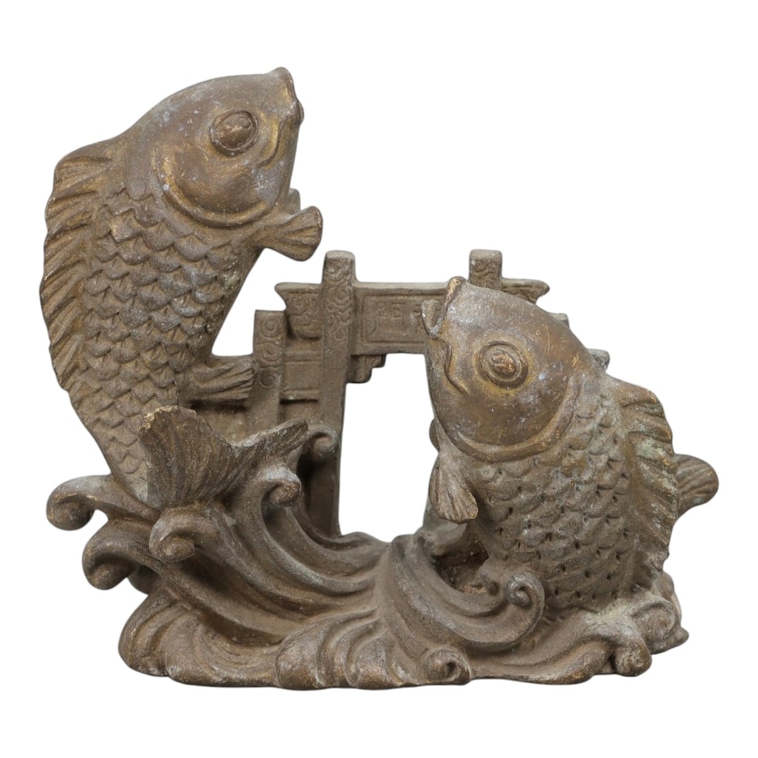 A Chinese Bronze Fish Group Display, 20th Century, 18FH: Cast in bronze, the object is formed as a pair of stylized fish emerging from curling waves, positioned on either side of a small architectural element resembling a gate or bridge. The fish are render