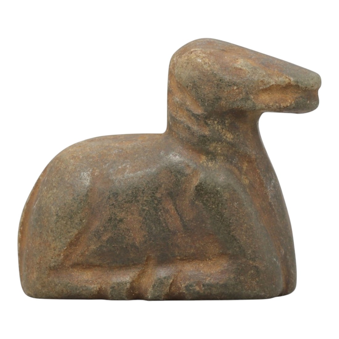 Ancient Stone Caprid Figurine - Near Eastern Carved Amulet, 62ZX: Carved from hard greenish stone, the figurine takes the form of a stylized recumbent caprid (sheep or goat), rendered in three dimensions with simplified anatomical carving. The head features a simpli