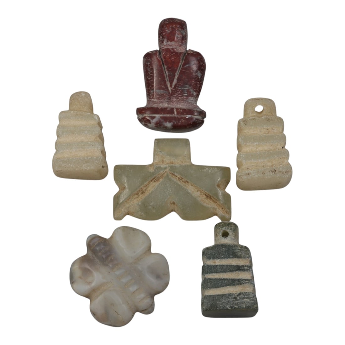 Lot of 6 Ancient Coptic Egyptian Stone Amulets, Circa Roman to Coptic Era, 92WP: Carved from various stones, including light beige, green, reddish-brown, and grey varieties, the group consists of six amulets of varied forms. The set includes stepped pyramid-shaped pendants, a seat
