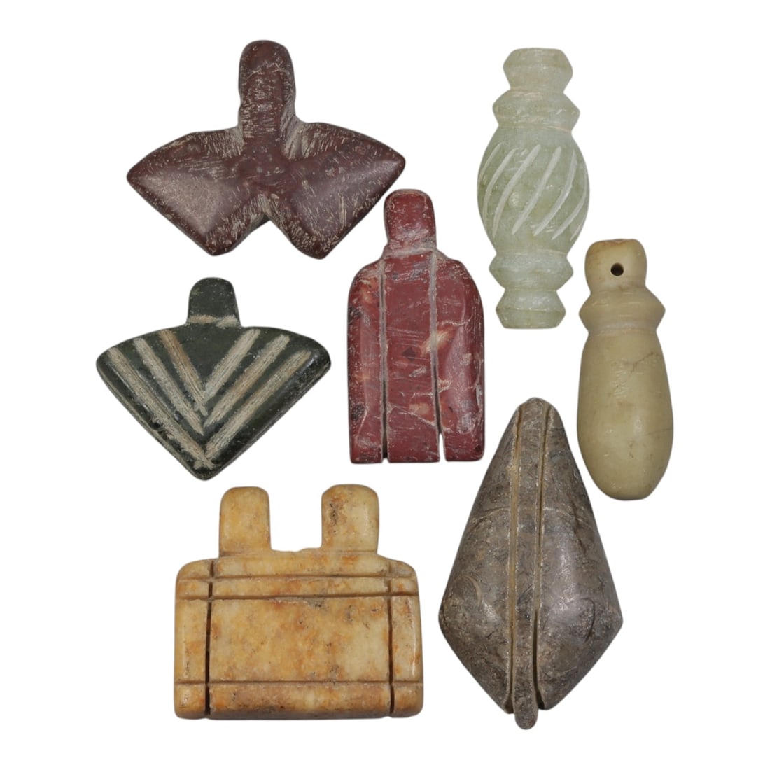 Lot of 7 Ancient Coptic Egyptian Multi-Stone Amulets, Circa Roman to Coptic Era, 97AH: Carved from various earth-toned stones including reddish-brown, green serpentine, light beige marble, and grey varieties, the group consists of seven distinct amulets, ranging in size from 2.5 cm to 4