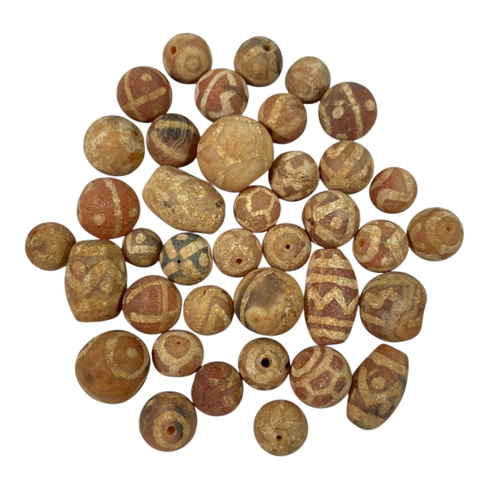 A Lot of 38 Ancient Etched Carnelian Beads, Gandhara Style, 70AA: This collection features 38 ancient etched carnelian beads, characteristic of Gandhara-period craftsmanship. Crafted from natural carnelian, they display warm reddish-brown and terracotta hues, adorne